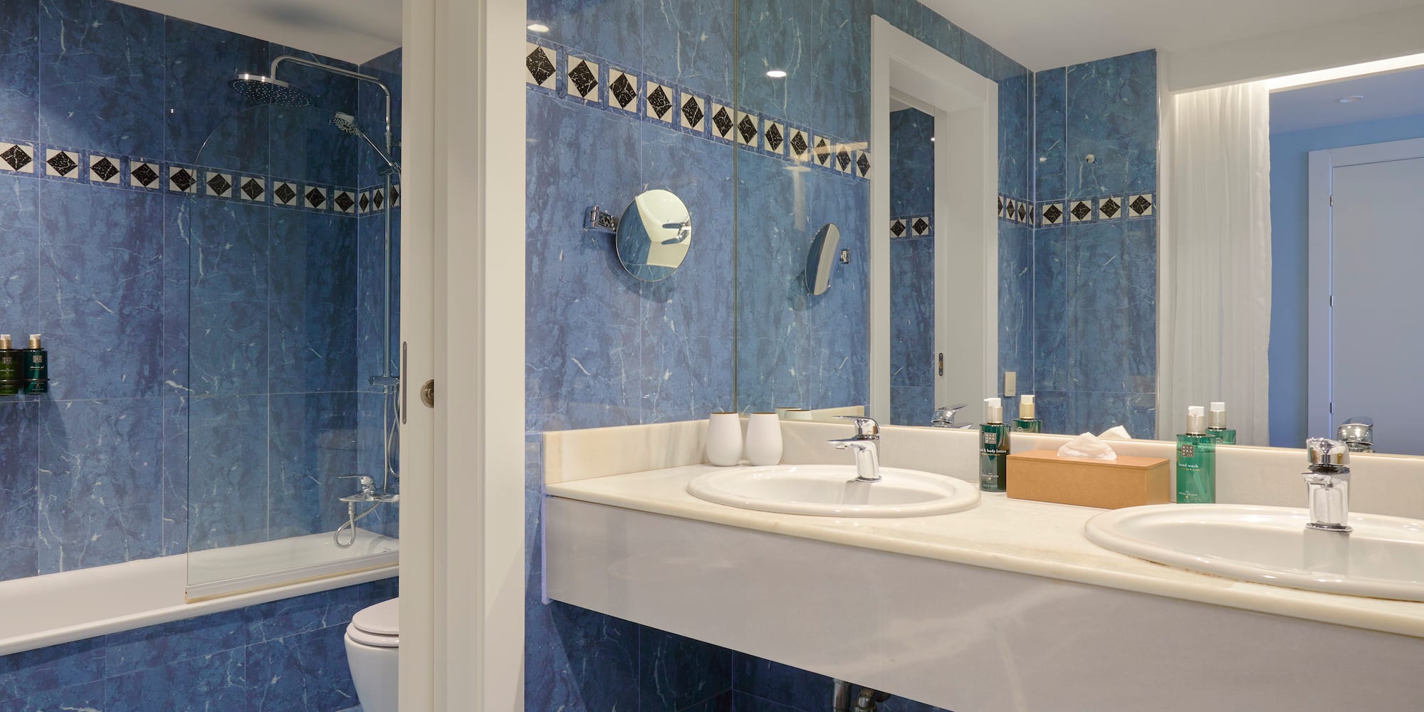a bathroom with blue tile walls and sinks
