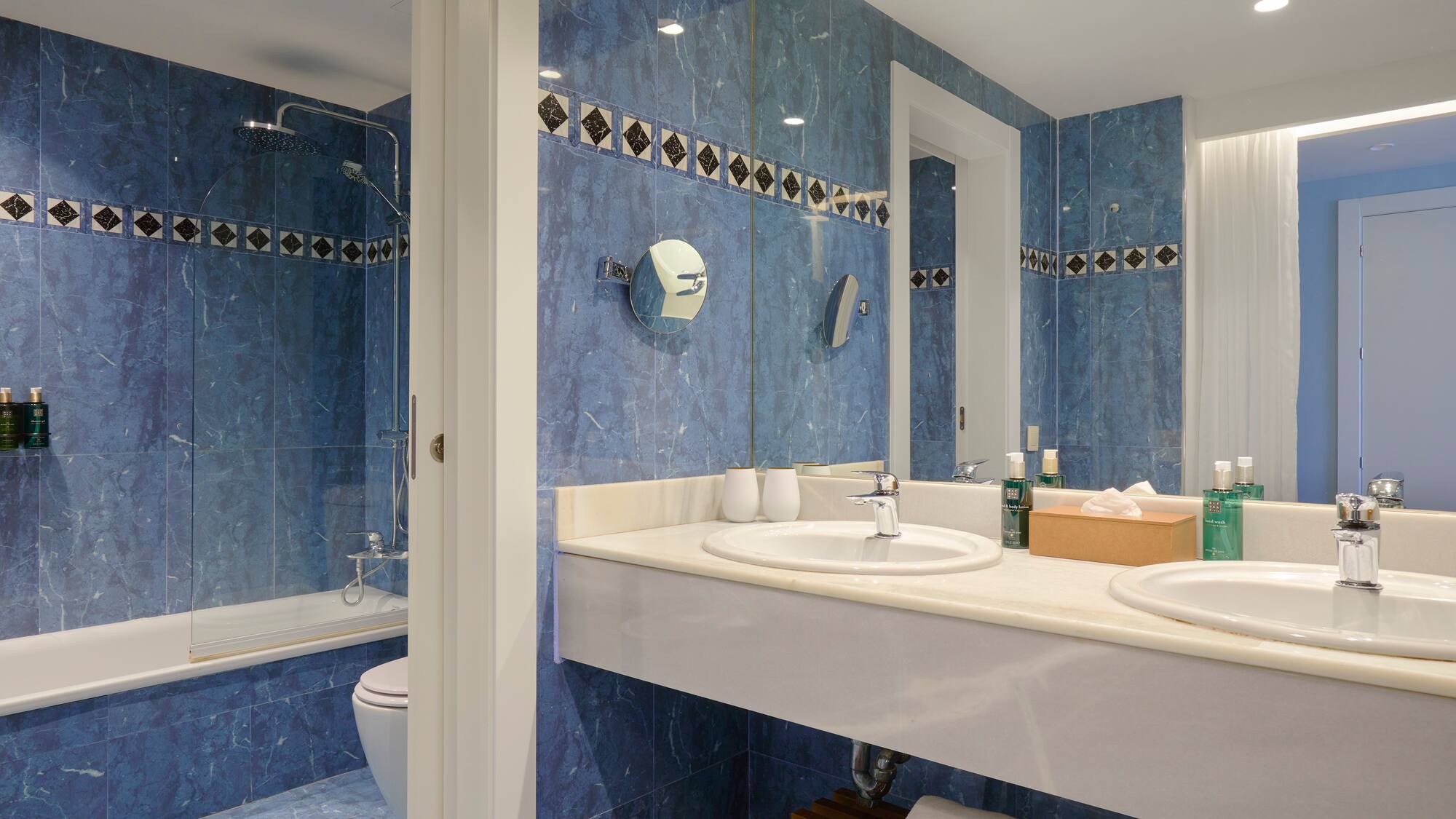 a bathroom with blue tile walls and sinks