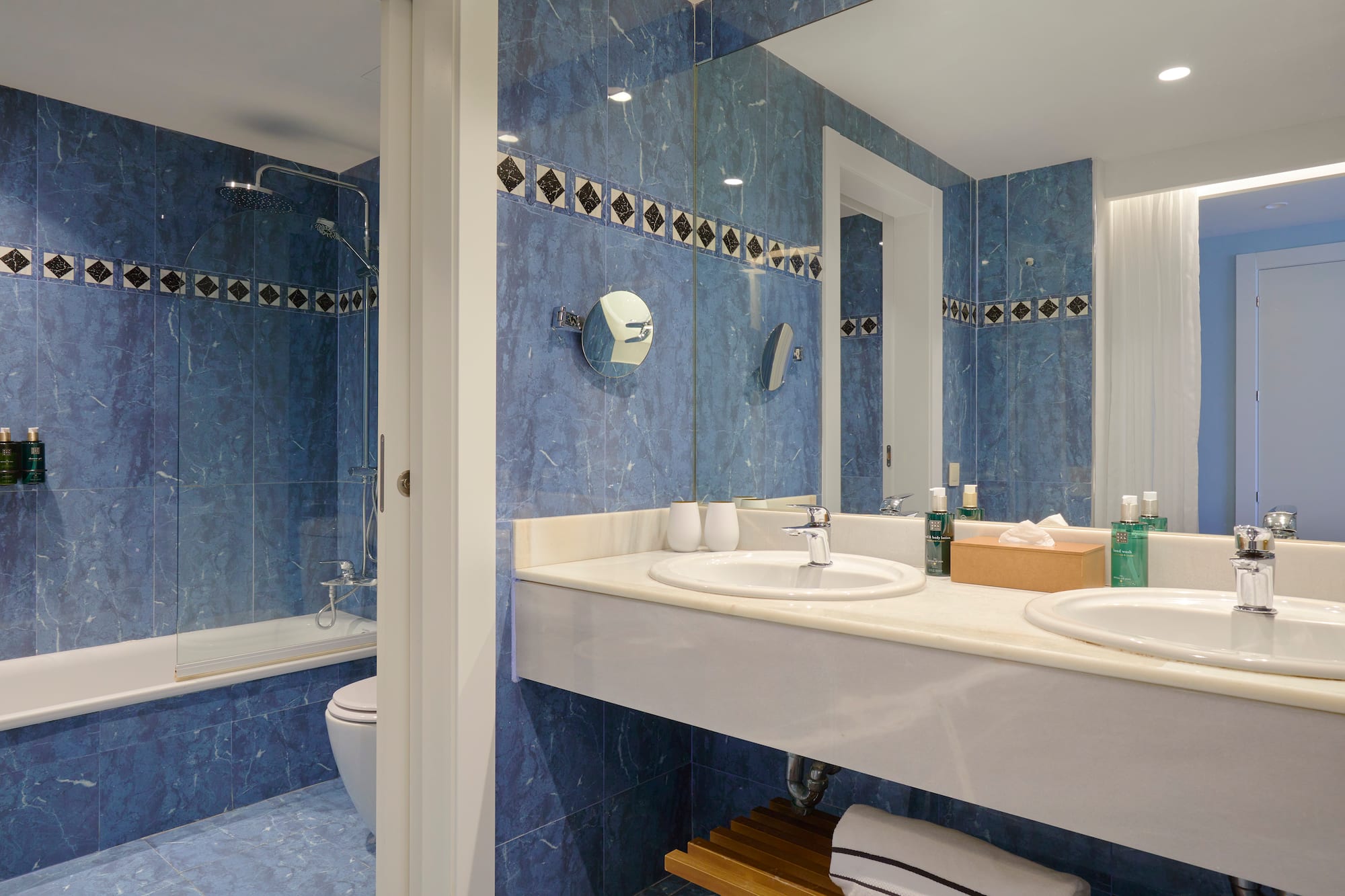 a bathroom with blue tile walls and sinks