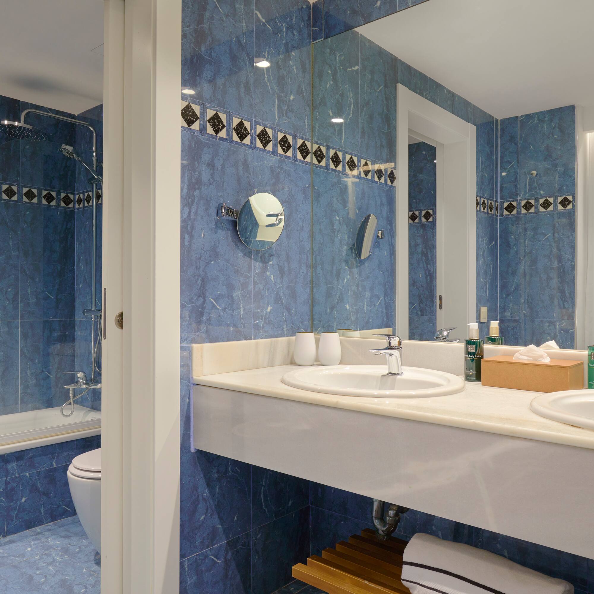 a bathroom with blue tile walls and sinks