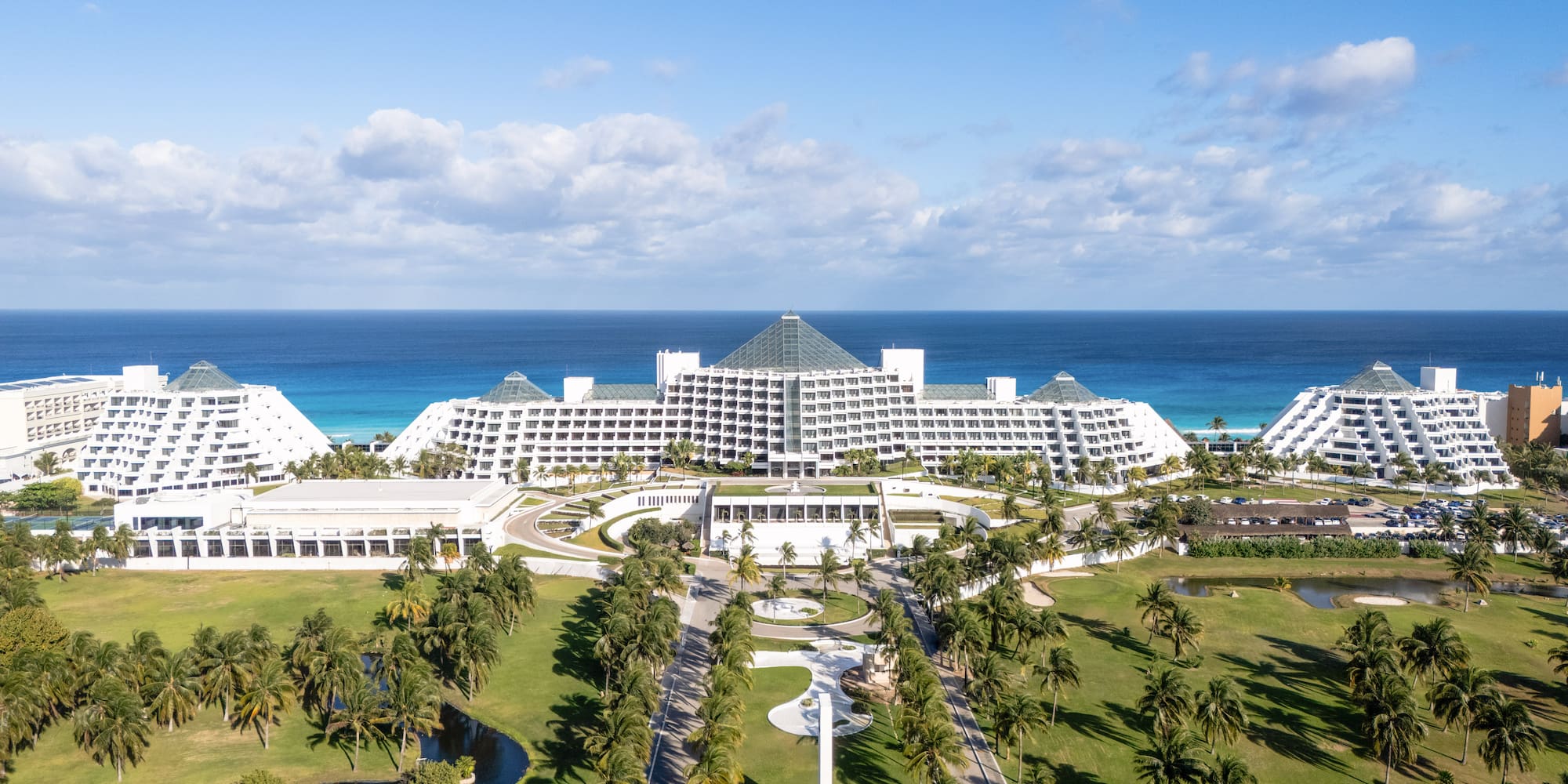 Cancun pyramid resort, oceanfront, with palm trees and golf course.