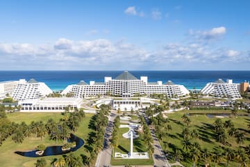 a large white building with a pool and palm trees