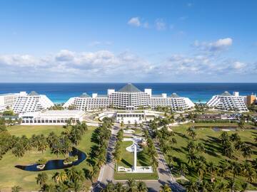 a large white building with a pool and palm trees