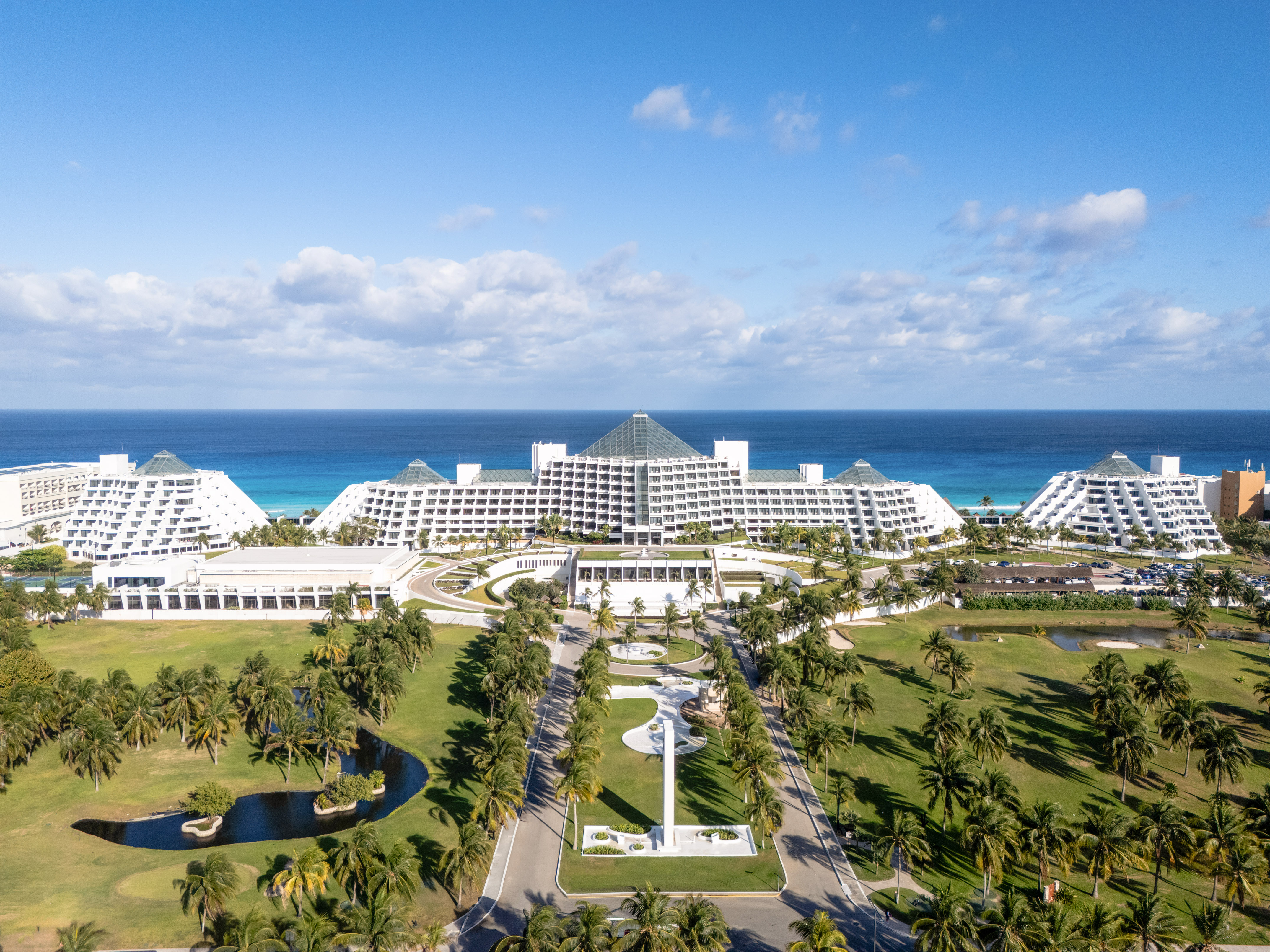 Cancun pyramid resort, oceanfront, with palm trees and golf course.