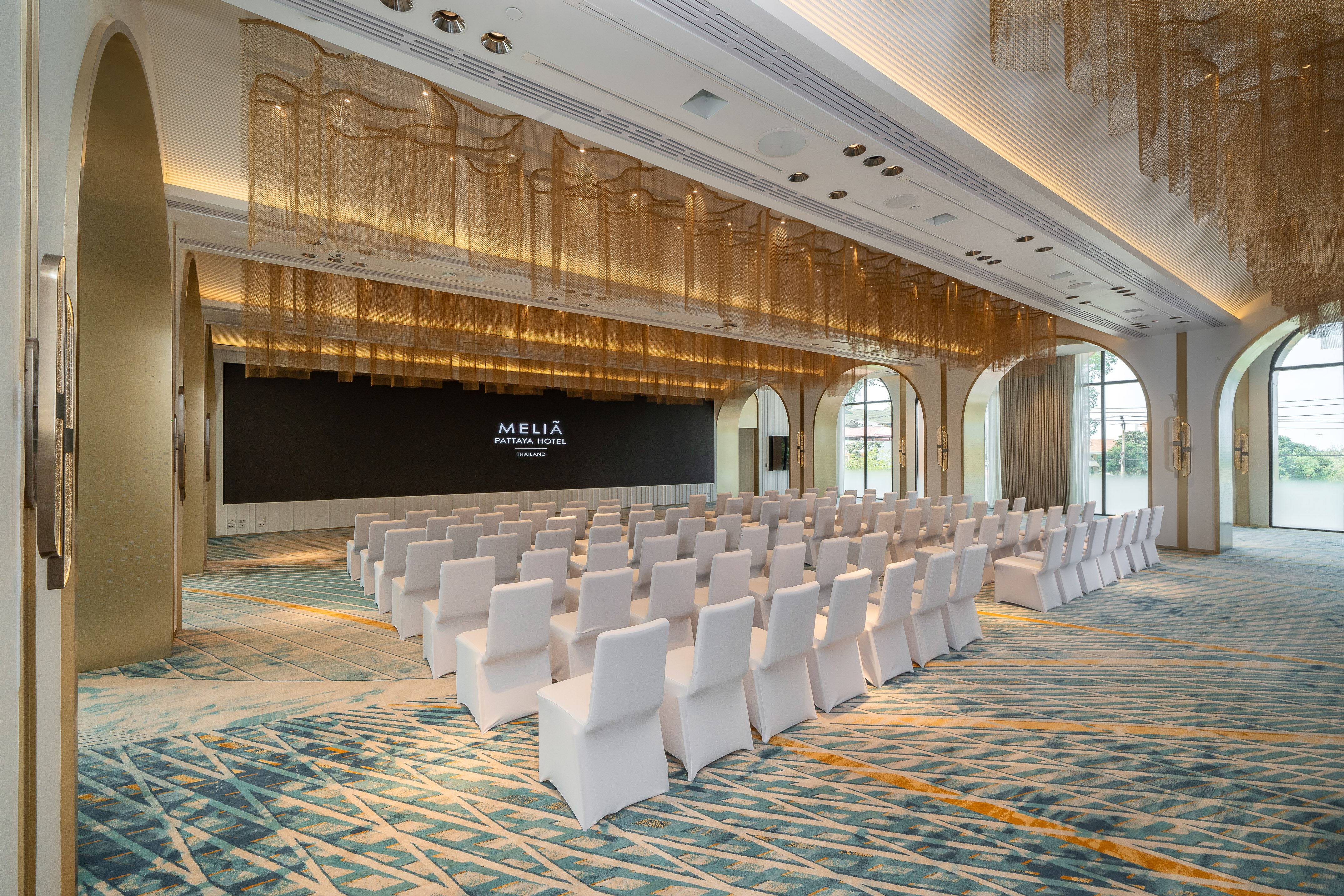 Elegant Meliã Pattaya Hotel meeting room with white chairs and gold ceiling.
