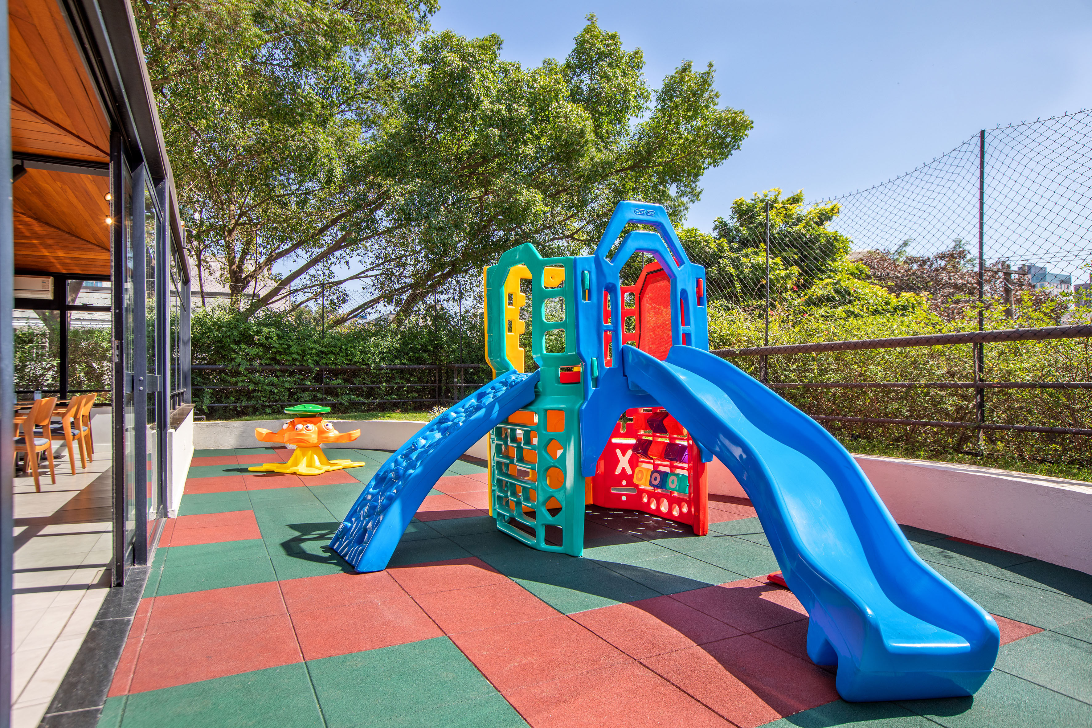 Colorful outdoor kids' playground with slides and climbing frame on safety mats.