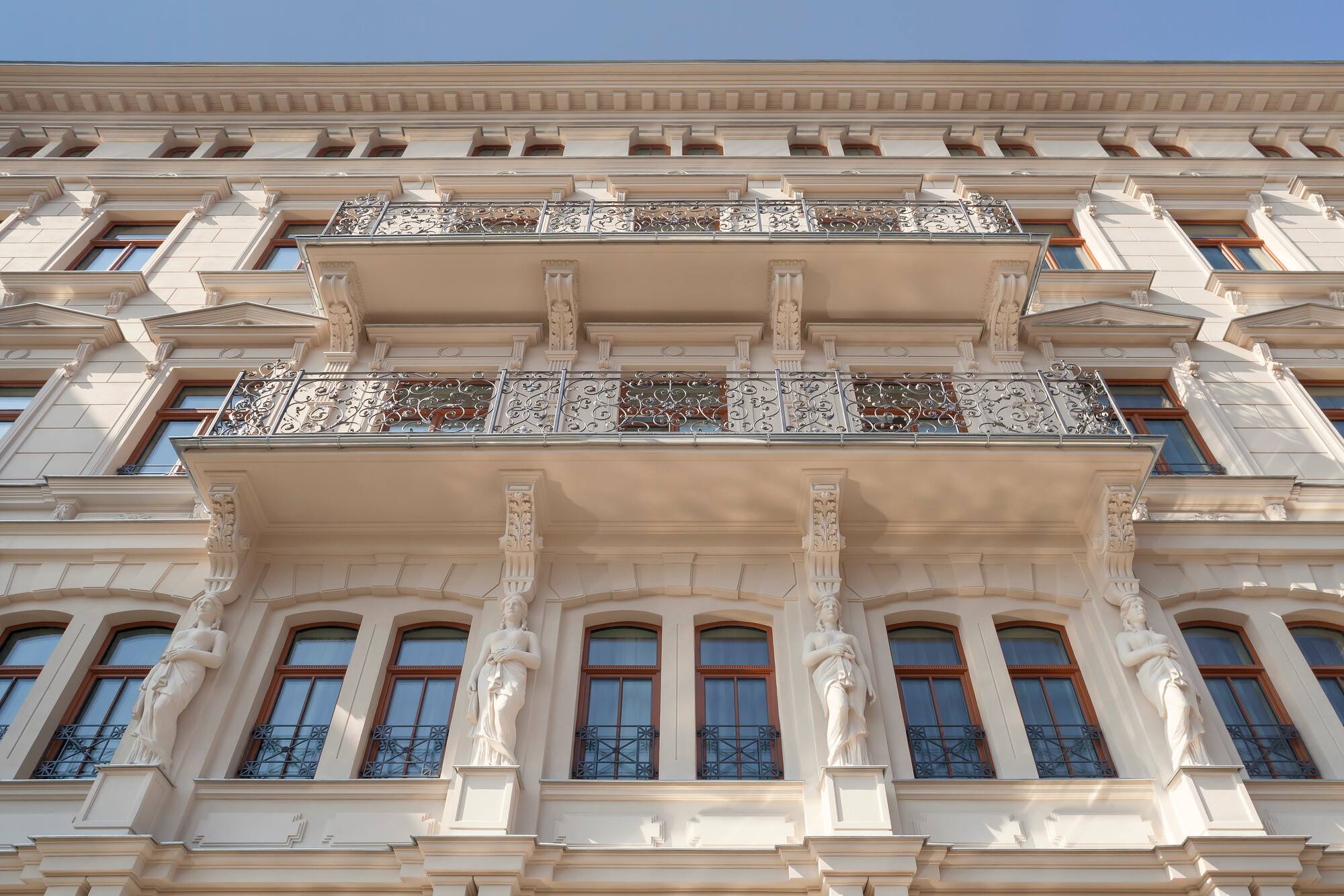 Historic building facade with ornate balconies, classical statues, arched windows.