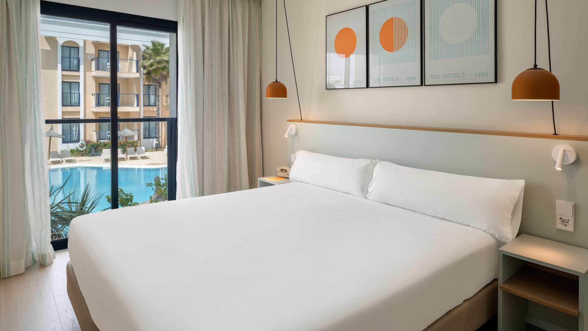 Modern Sol Hotels bedroom with large bed and swimming pool view.