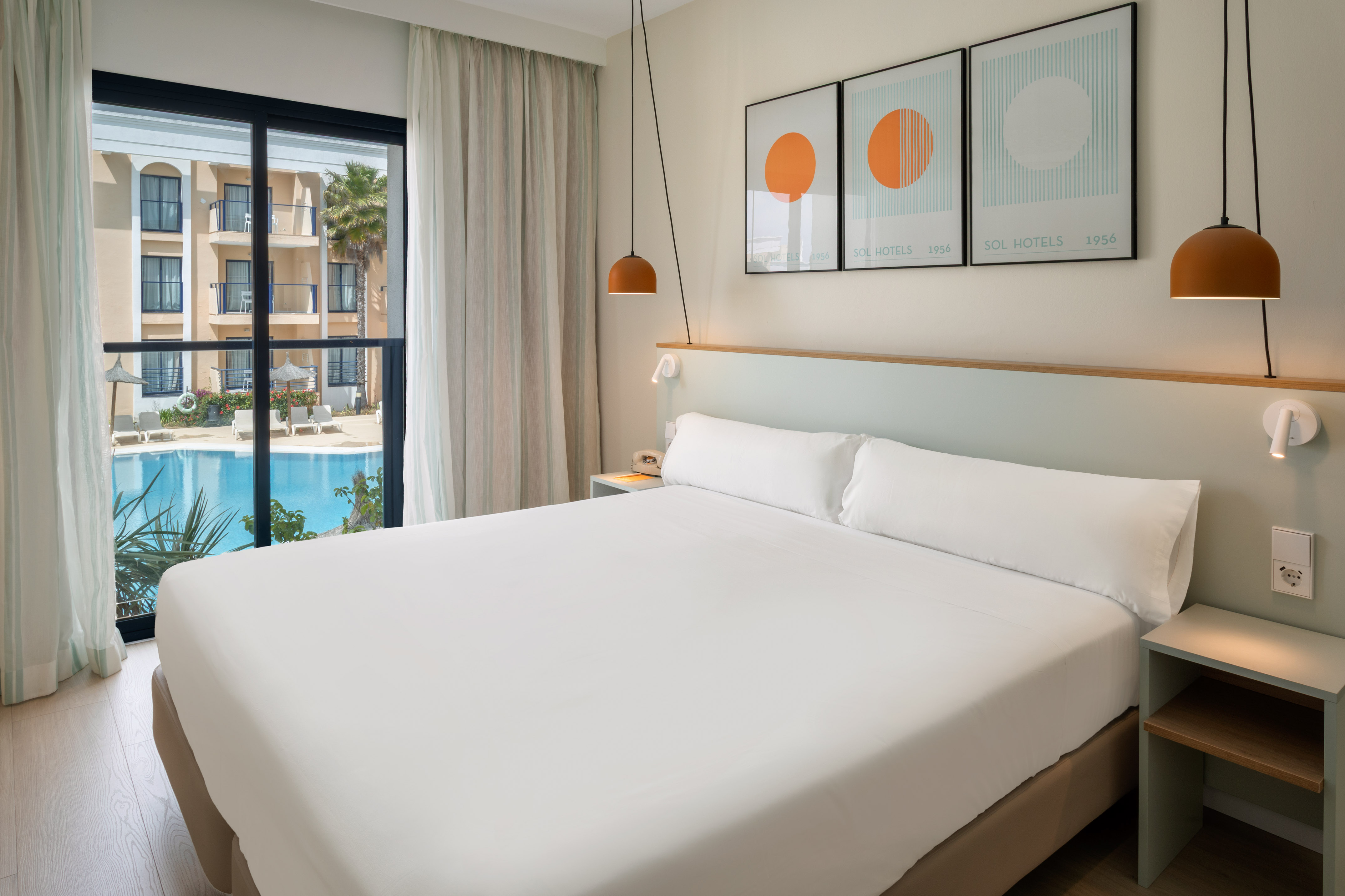 Modern Sol Hotels bedroom with large bed and swimming pool view.