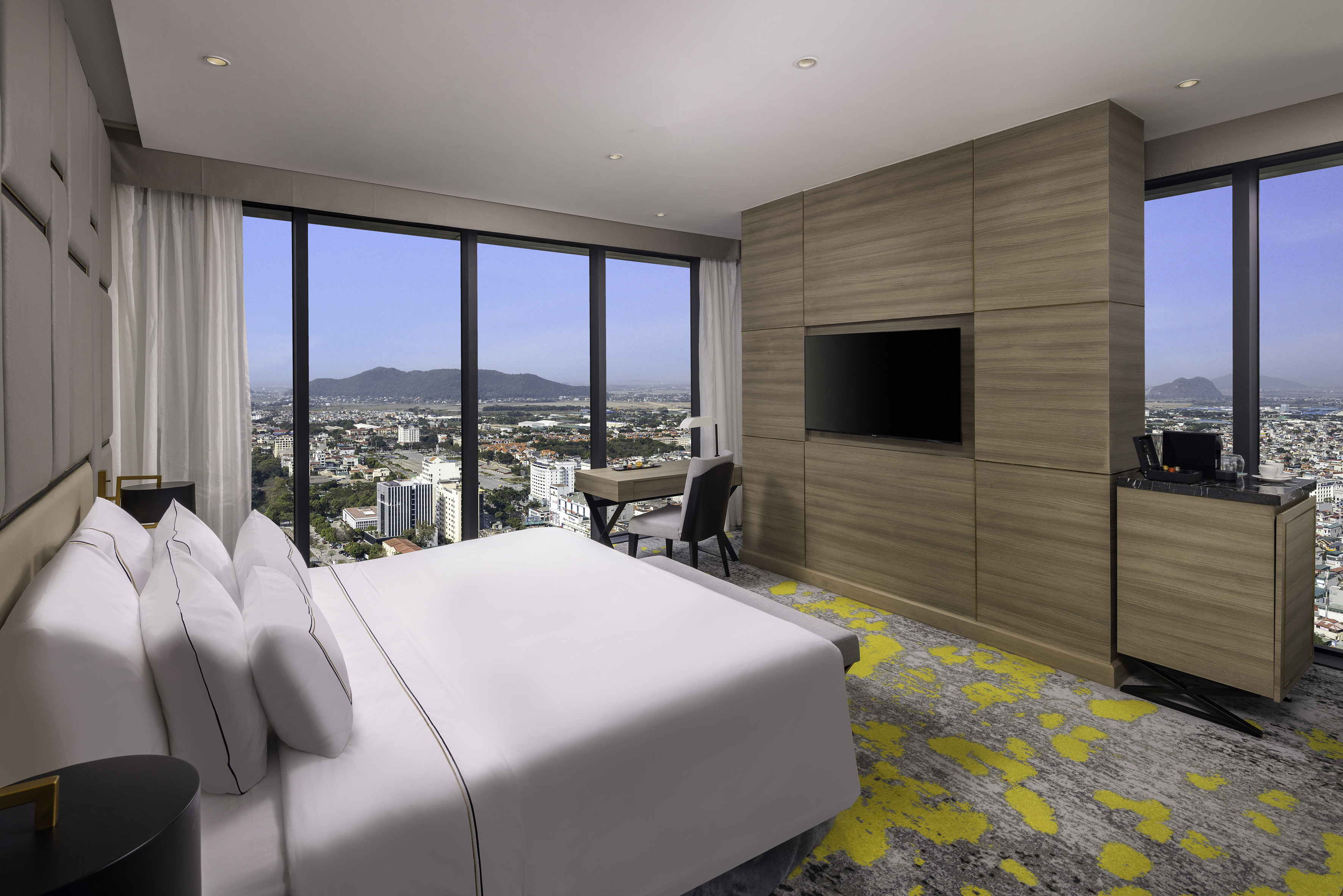Modern hotel room with panoramic city and mountain views.