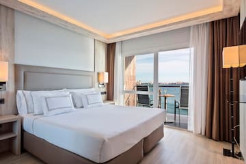 a bedroom with a large bed and a balcony overlooking the water
