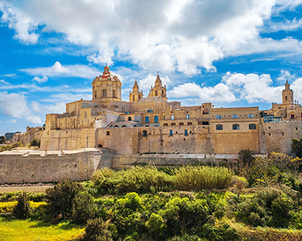 Mdina, Malta: historic fortified city with cathedral domes against blue sky.