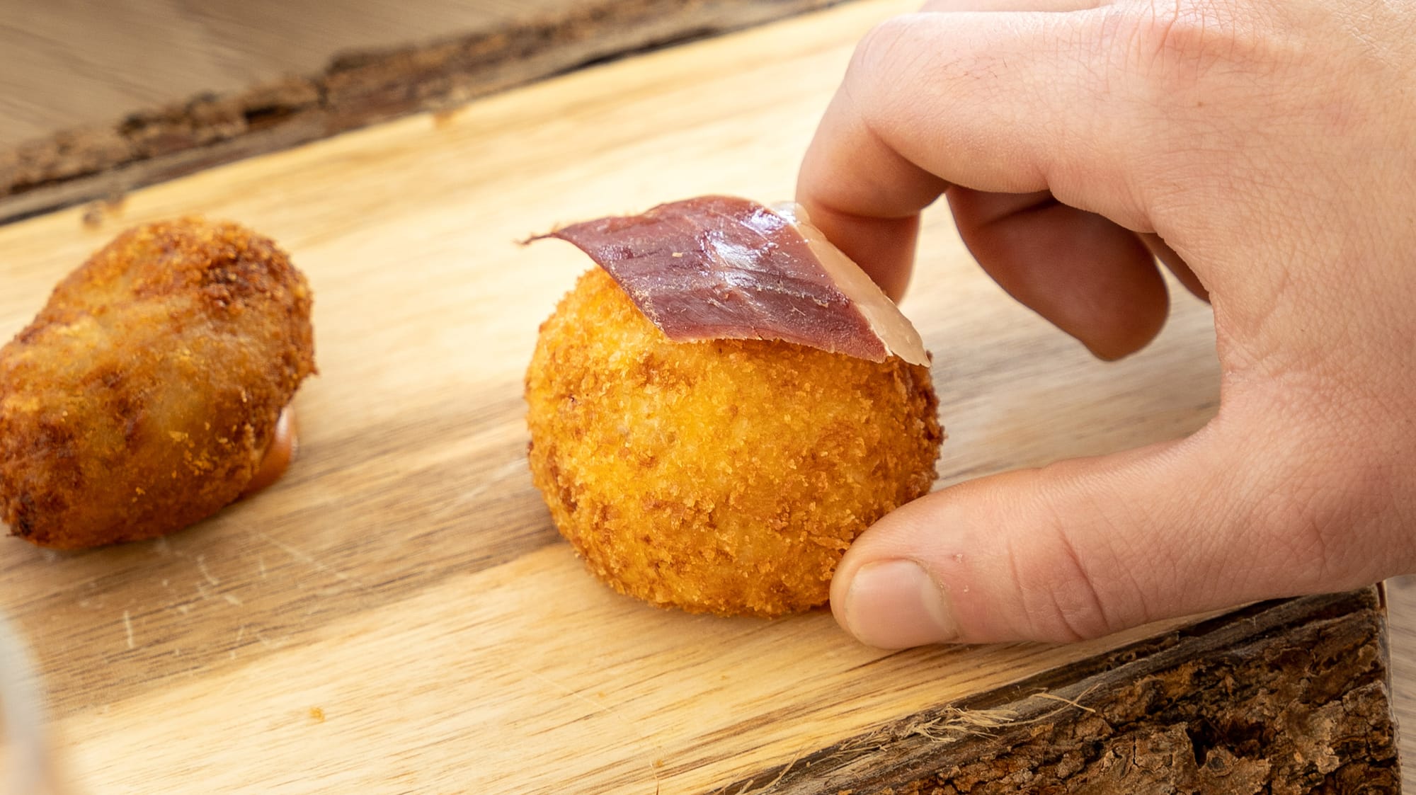 a hand holding a round object with meat on it