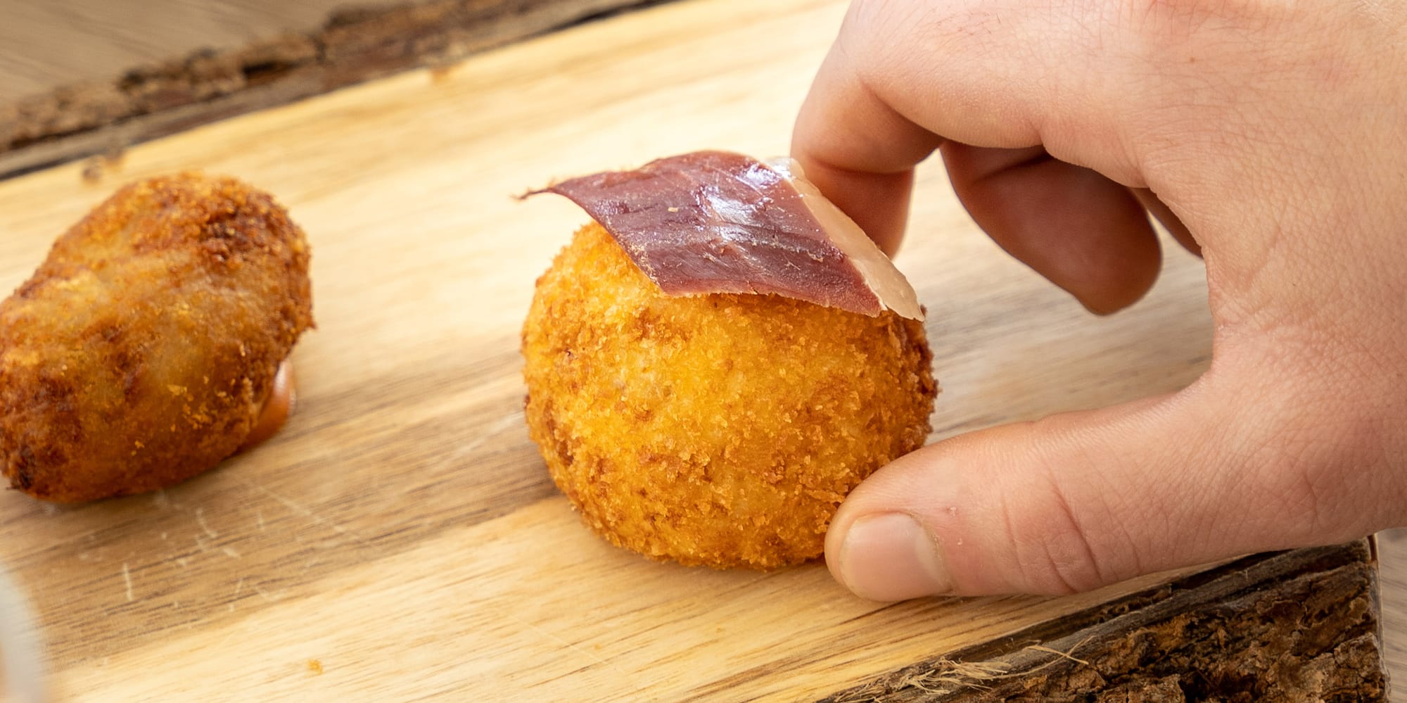 a hand holding a round object with meat on it