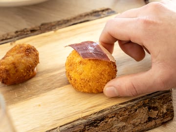 a hand holding a round object with meat on it