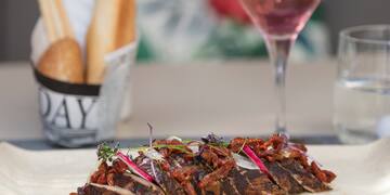 a sliced meat with onions and herbs on a table