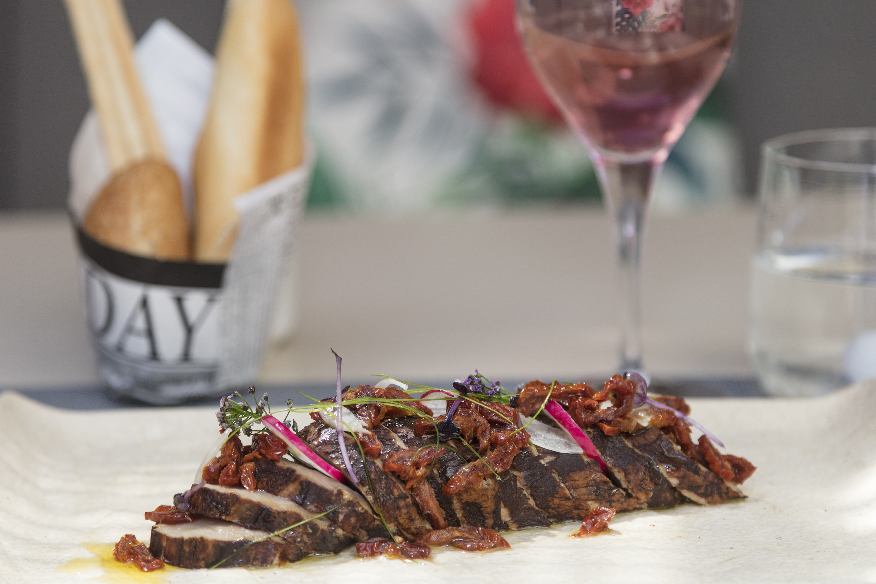 Sliced roasted meat with sun-dried tomatoes, onion, herbs, and rosé wine.