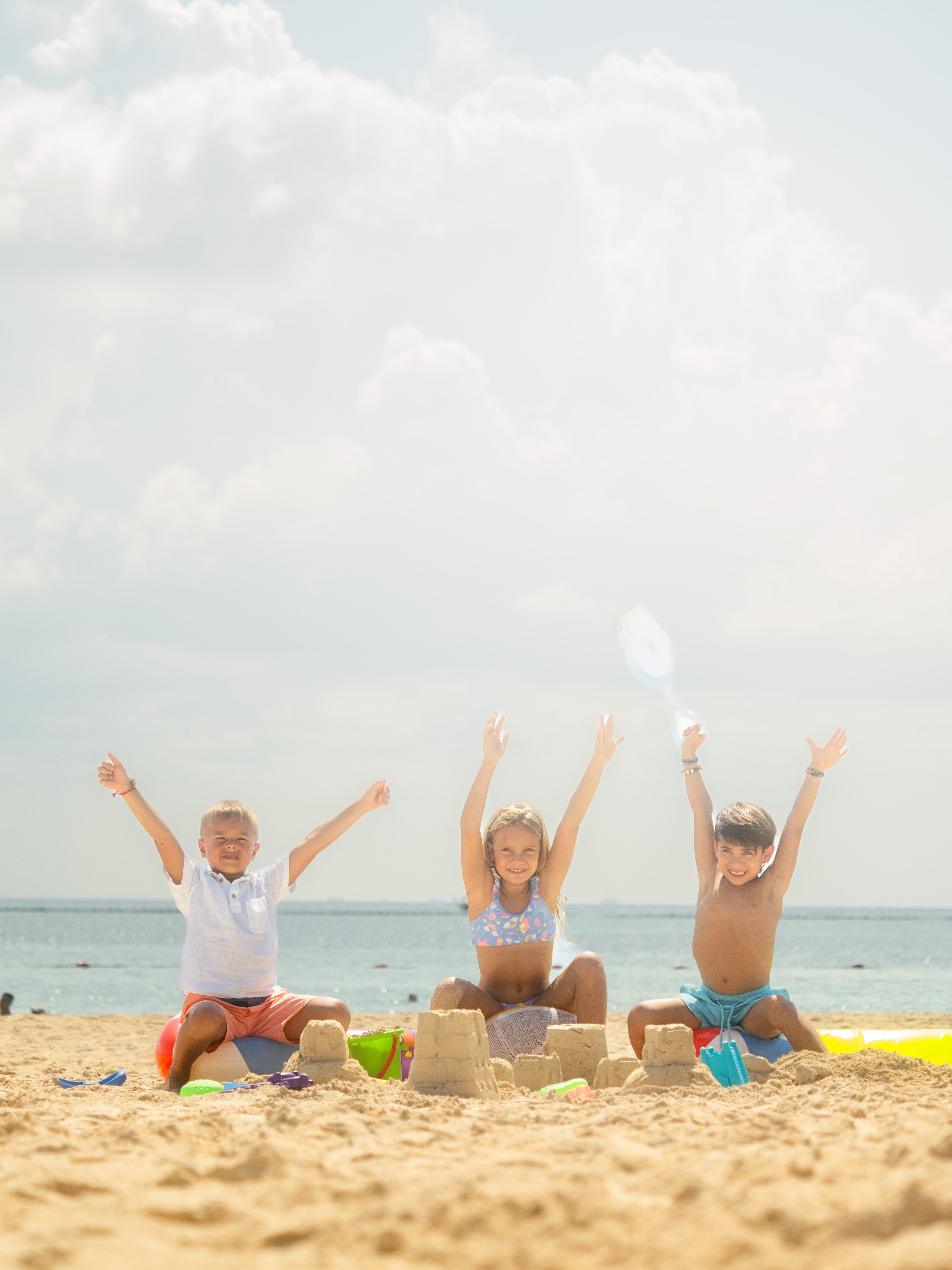 a group of kids sitting on sand on a beach