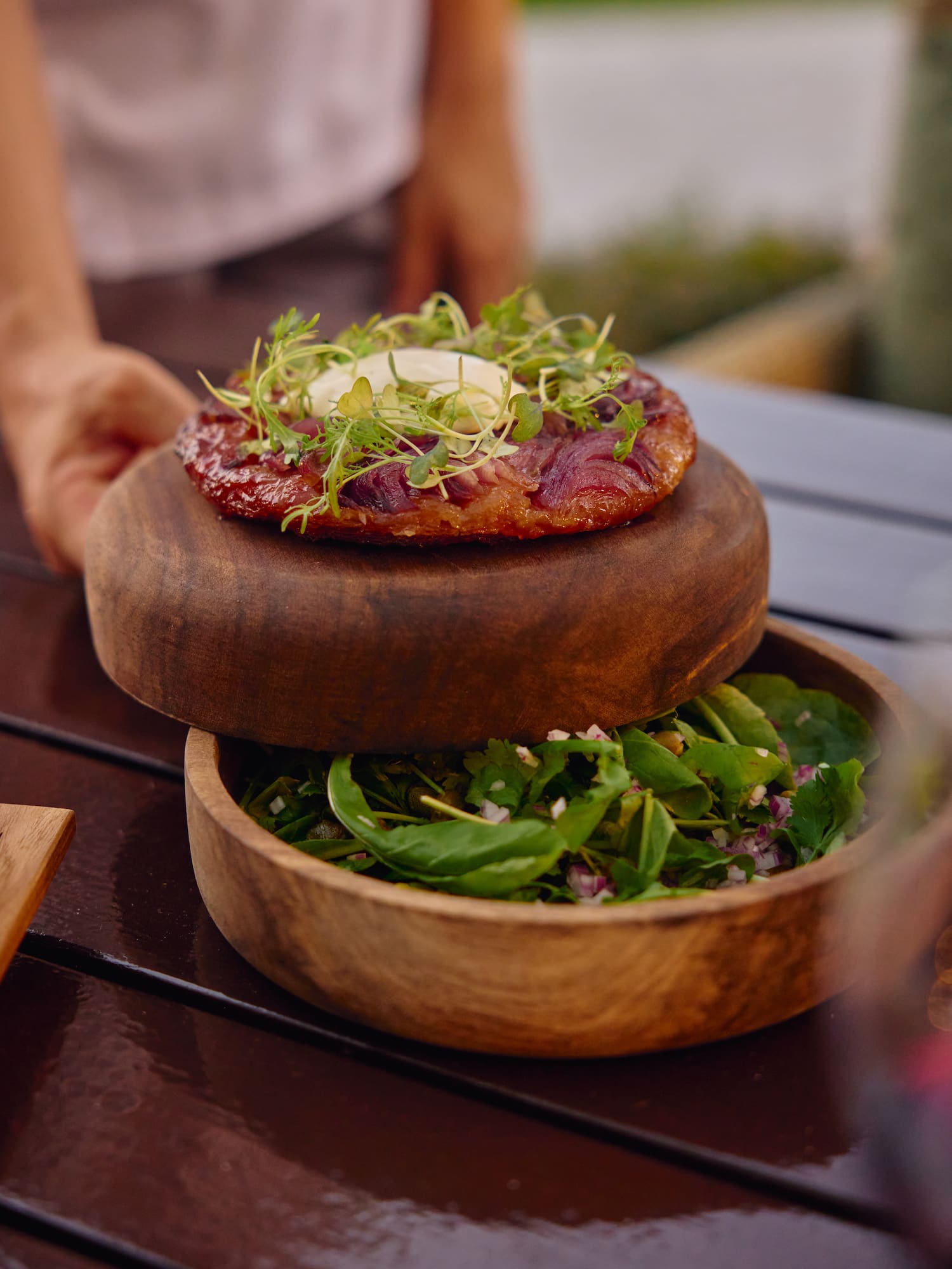 Tarta Tatin de cebolla, microvegetales y ensalada fresca en madera.