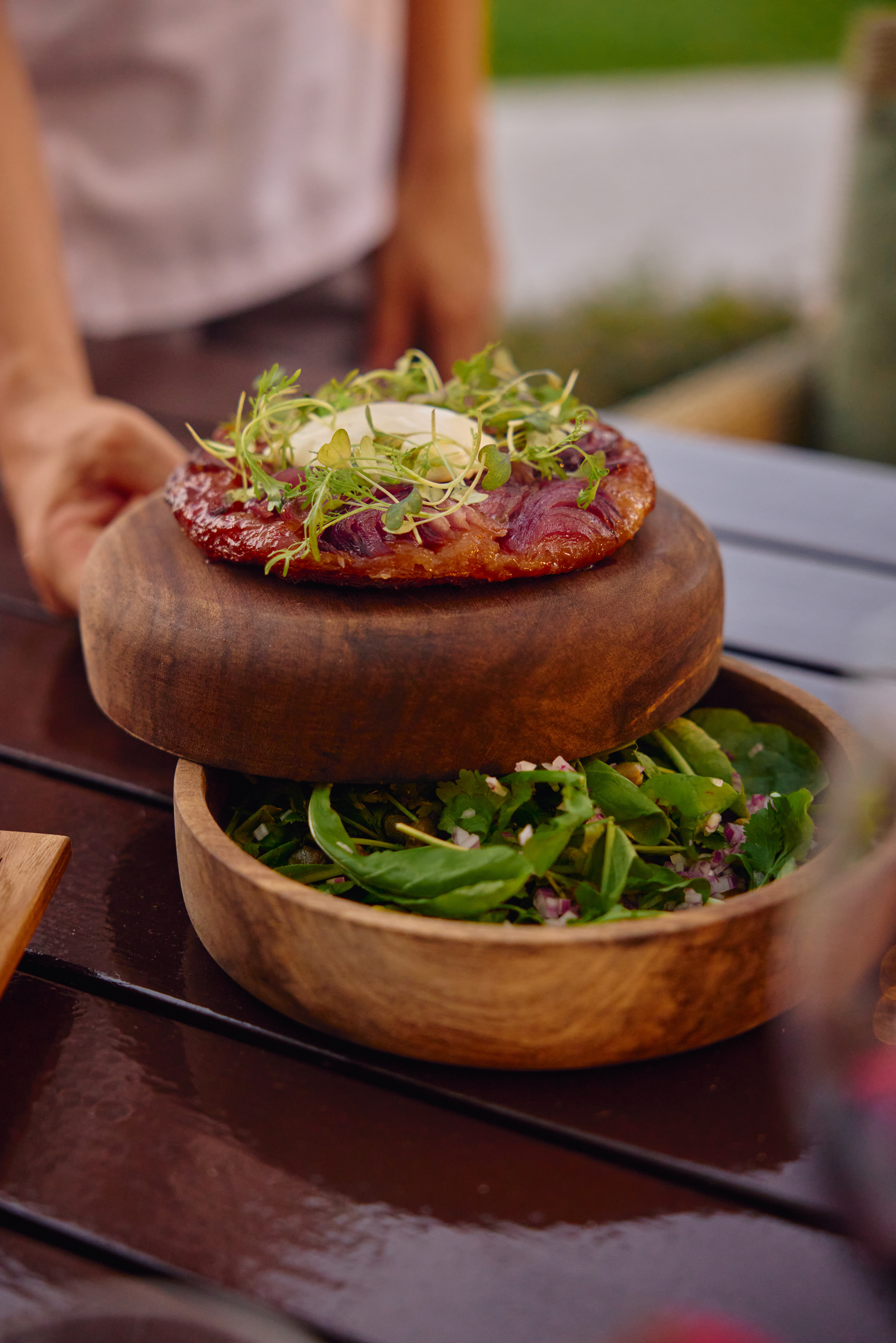 Tarta Tatin de cebolla, microvegetales y ensalada fresca en madera.