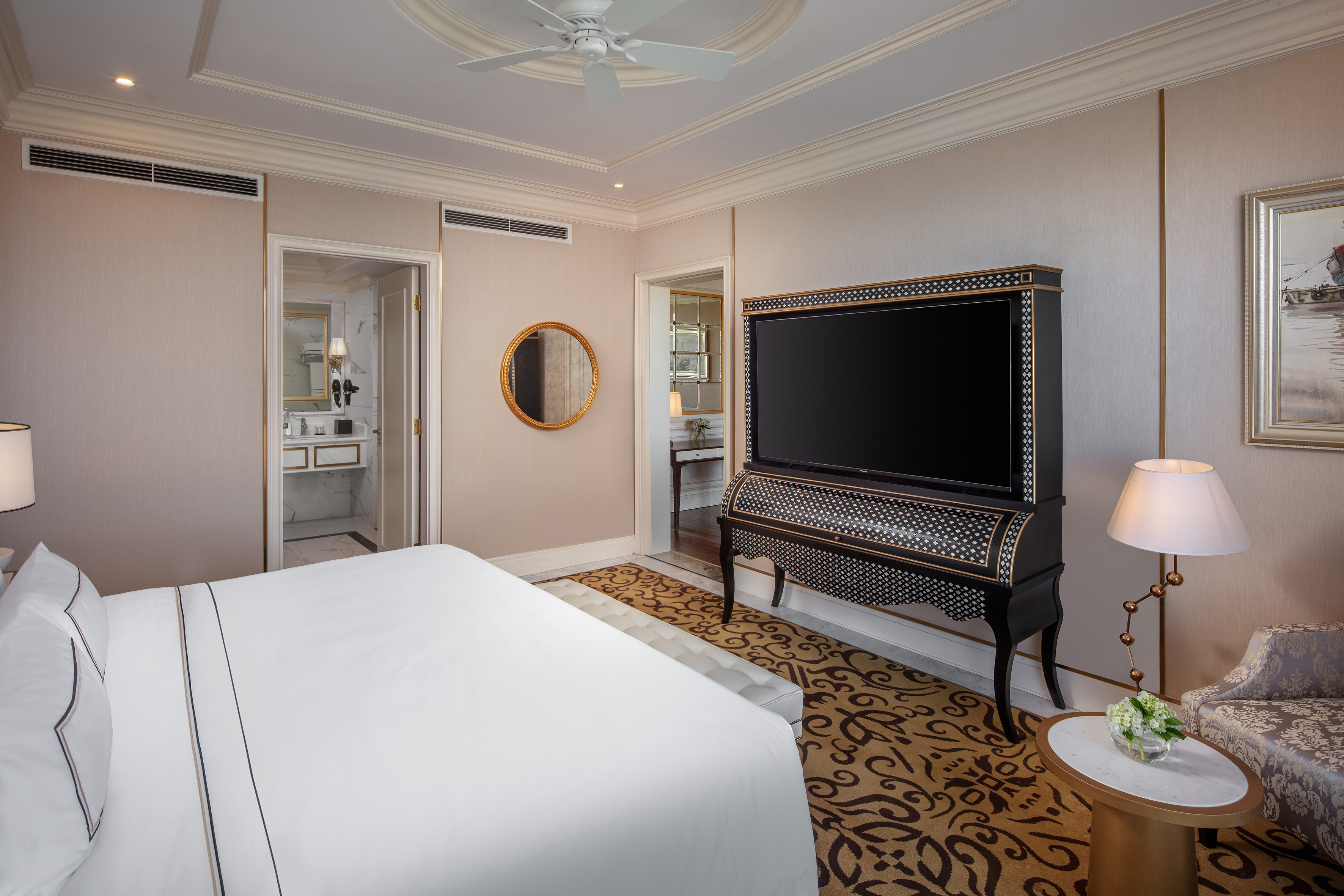 Elegant hotel room with bed, large TV cabinet, and luxurious interior design.