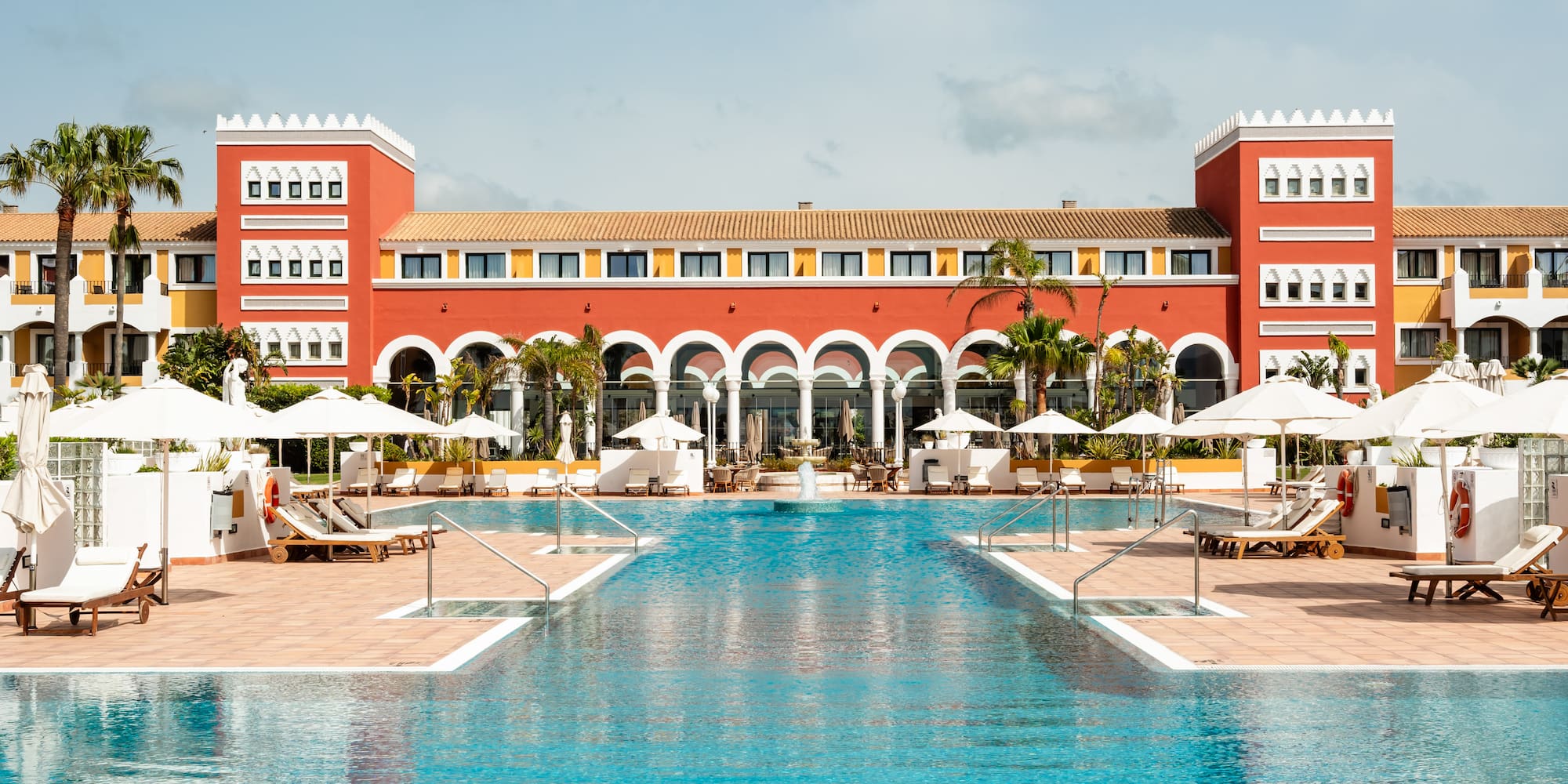 a pool with chairs and umbrellas in front of a building