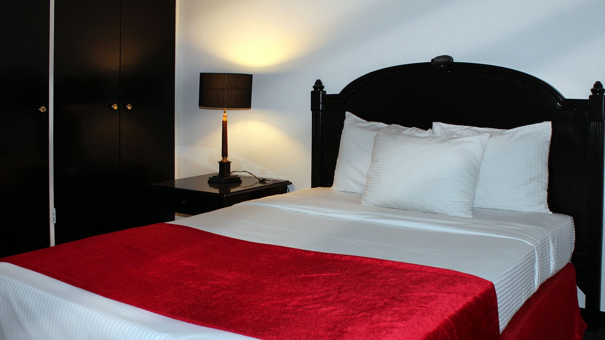 a bed with a red blanket and a lamp