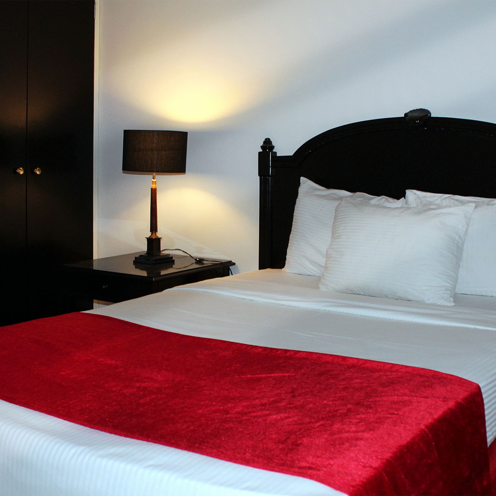 a bed with a red blanket and a lamp