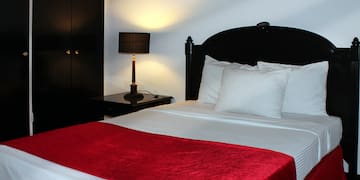 a bed with a red blanket and a lamp