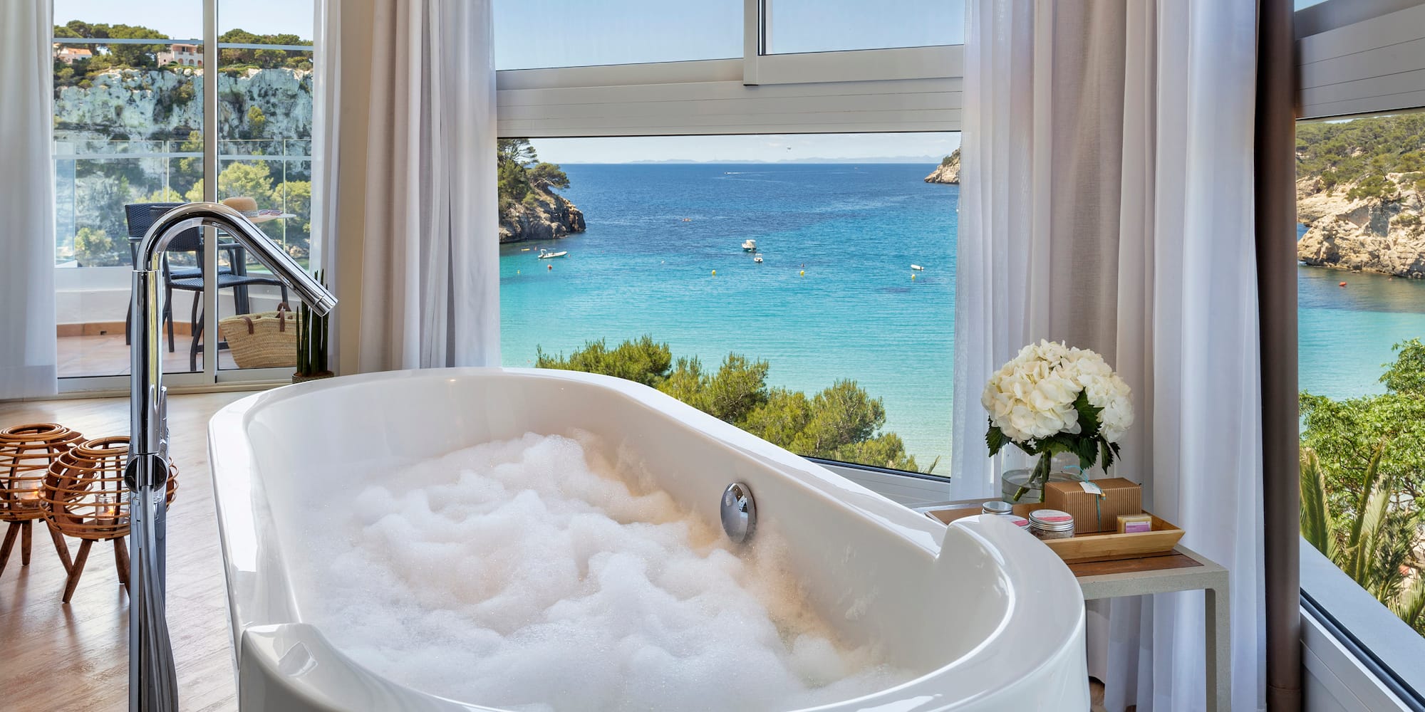 a bathtub with bubbles in front of a window overlooking a body of water