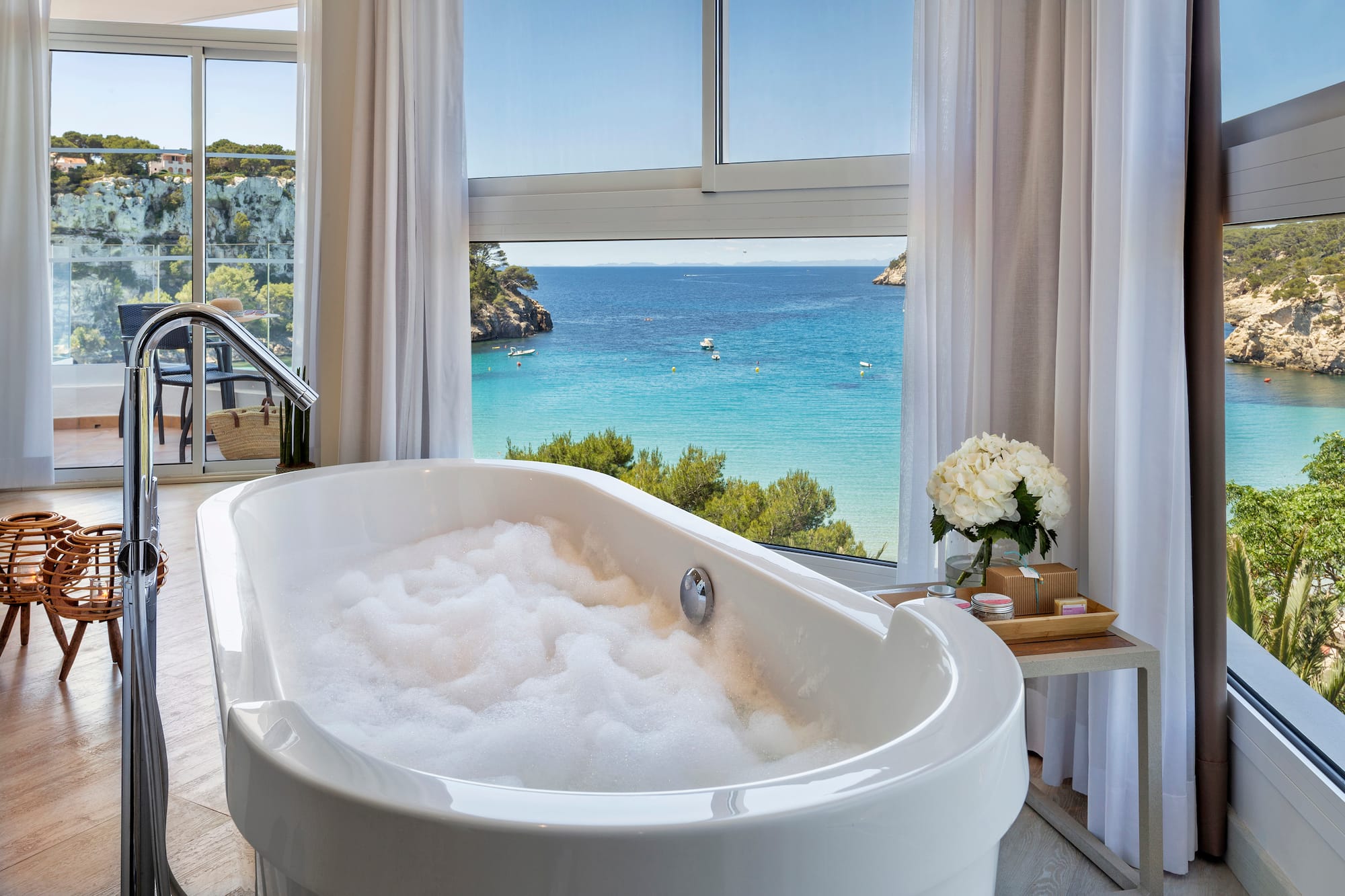 a bathtub with bubbles in front of a window overlooking a body of water