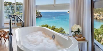 a bathtub with bubbles in front of a window overlooking a body of water