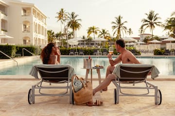 a man and woman sitting in lounge chairs by a pool