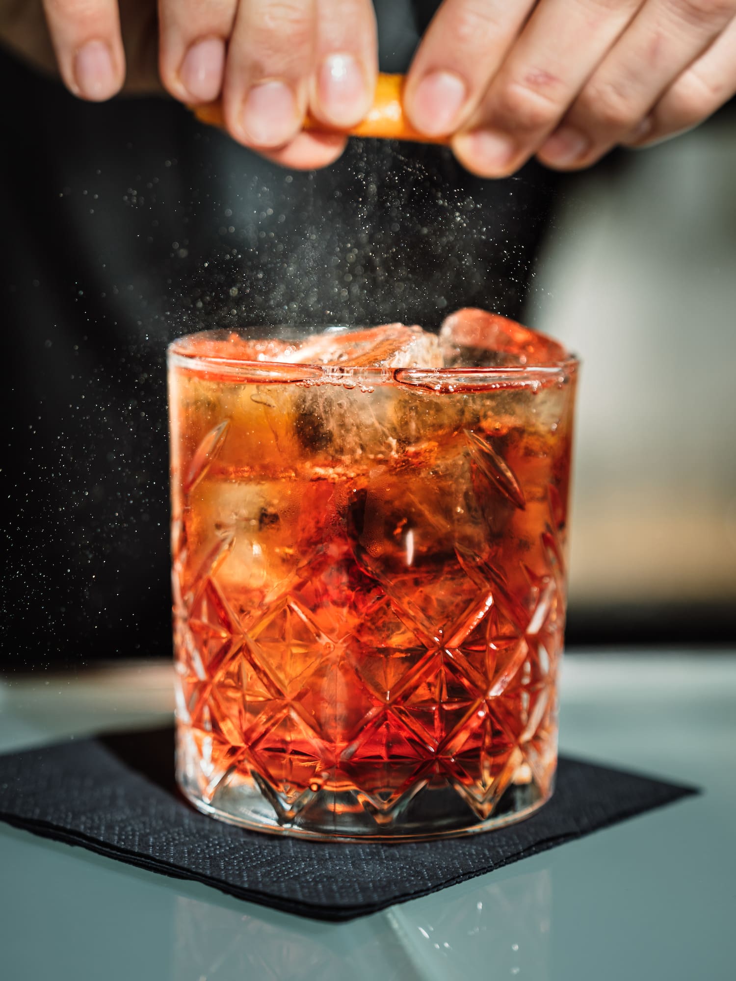 a person sprinkling a drink into a glass