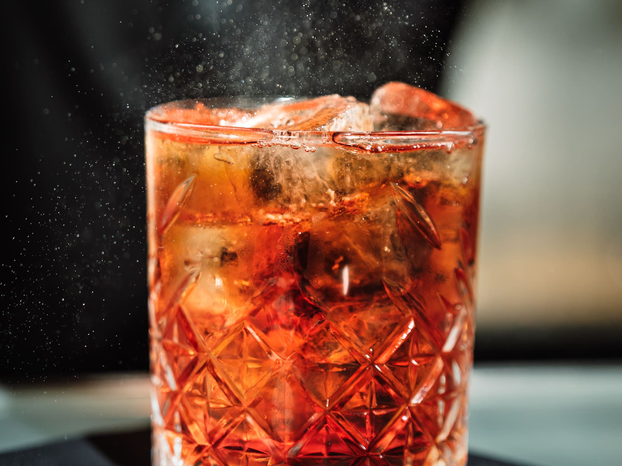 a person sprinkling a drink into a glass