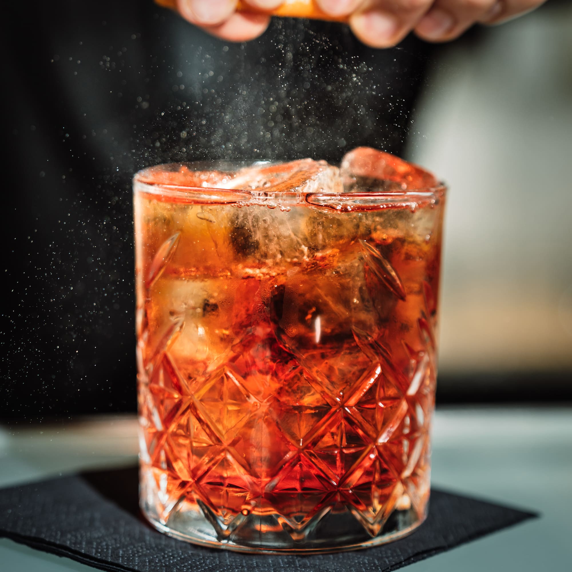 a person sprinkling a drink into a glass
