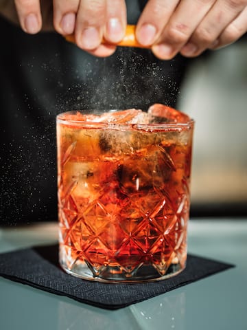 a person sprinkling a drink into a glass