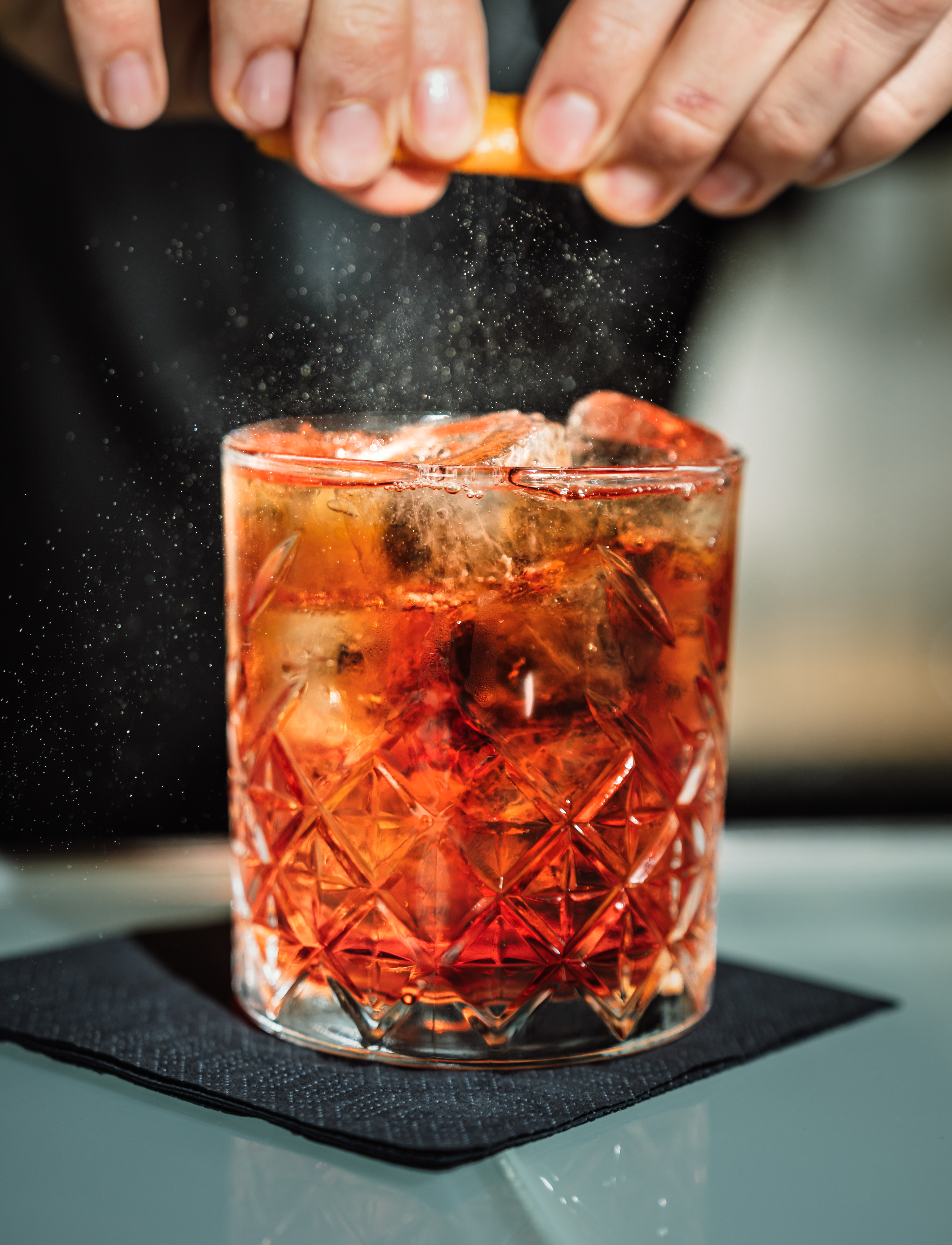 a person sprinkling a drink into a glass