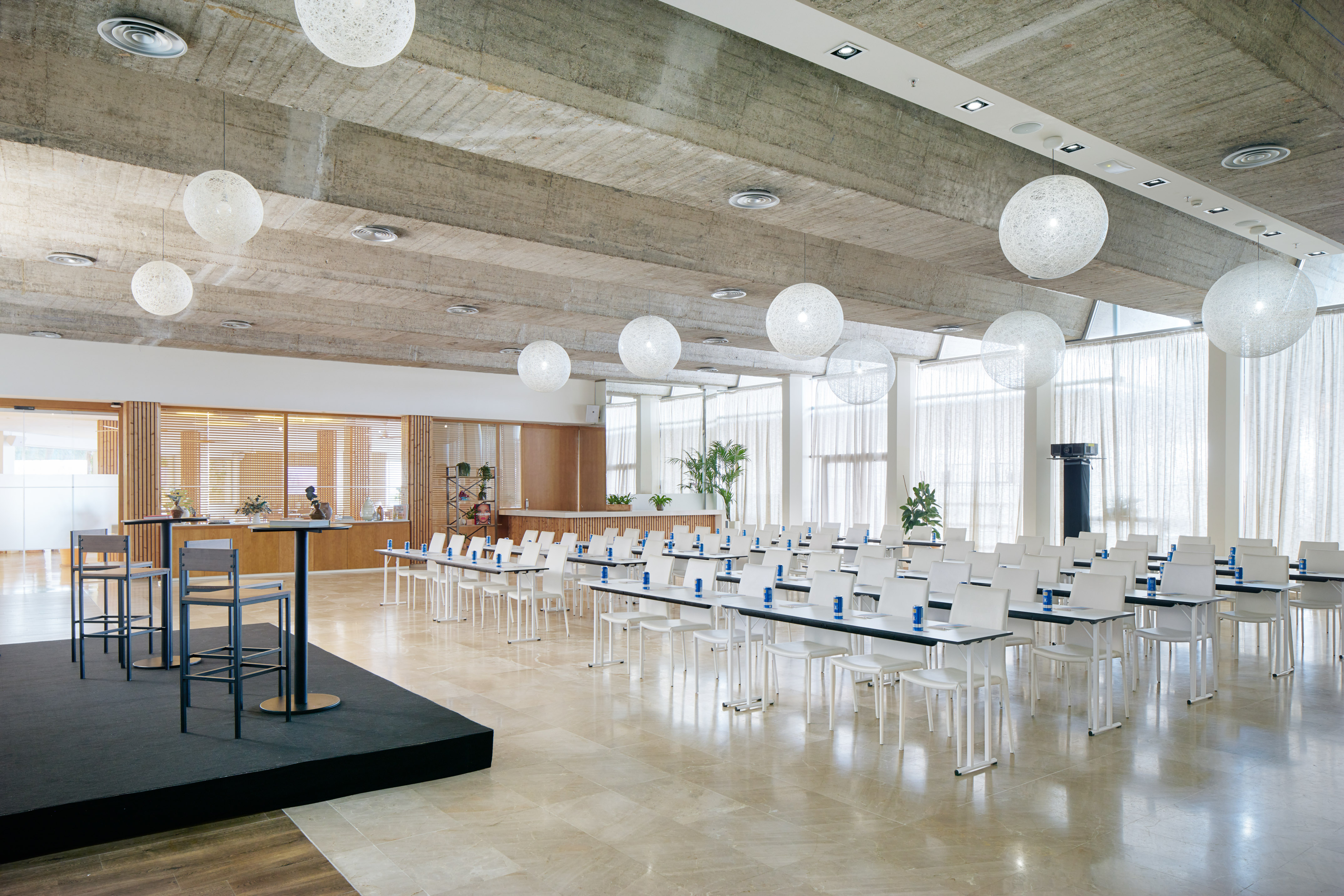 Modern conference room with presentation setup, white tables, and stage.