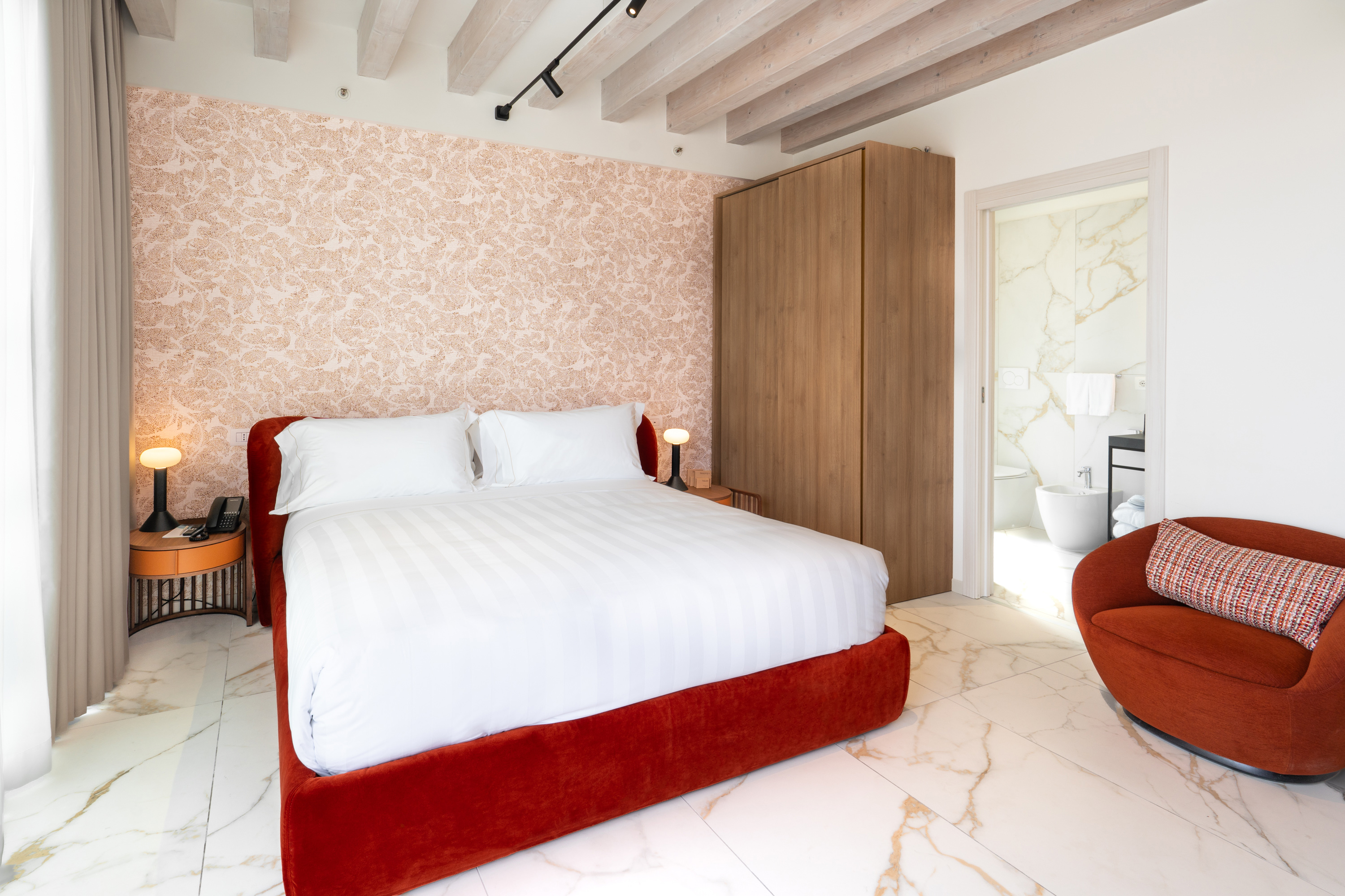 Modern hotel room, red bed, patterned wall, marble floor, en-suite.