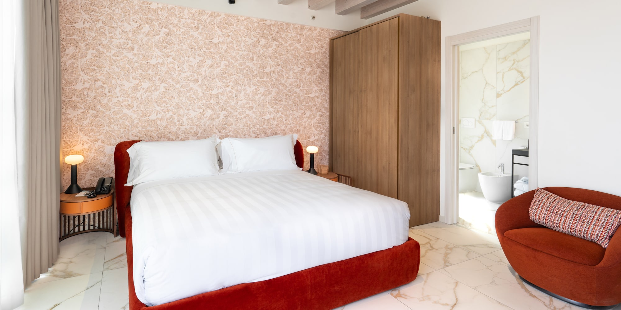 Modern hotel room, red bed, patterned wall, marble floor, en-suite.