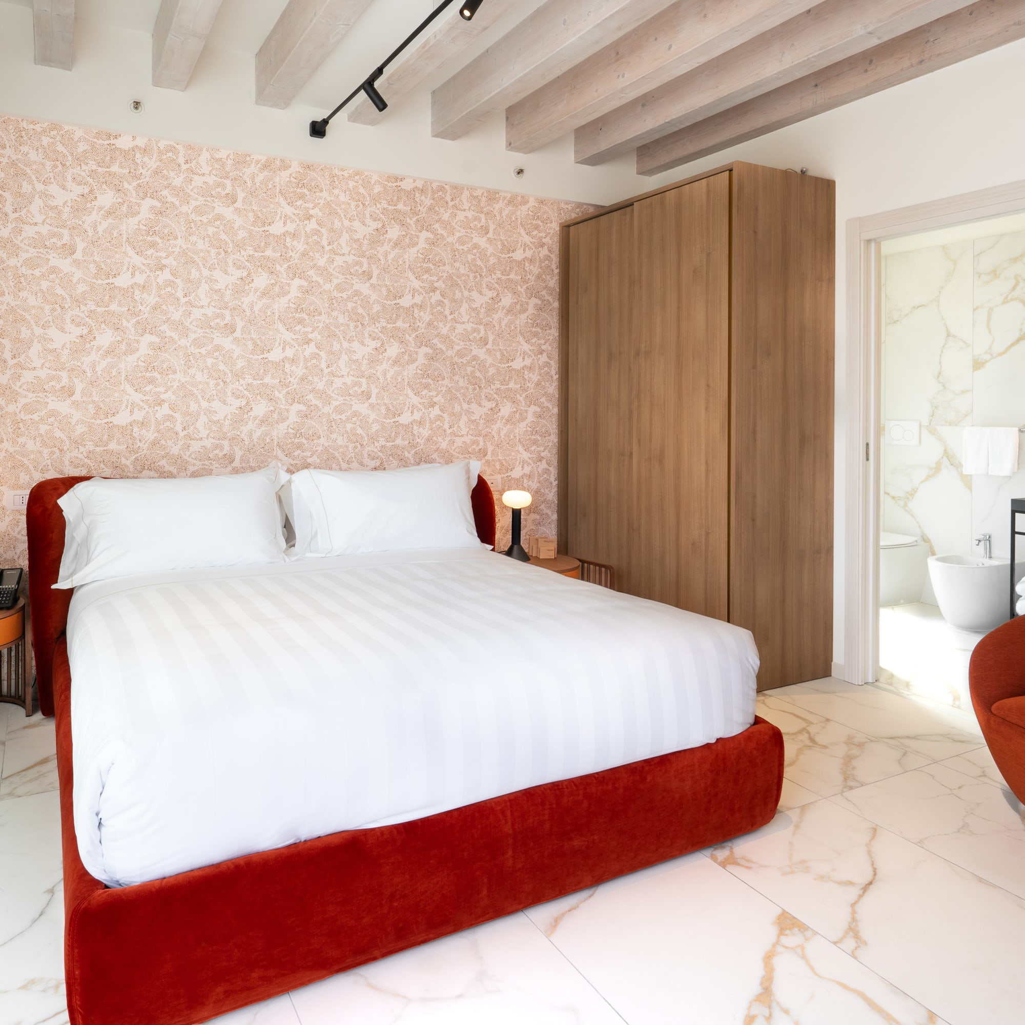 Modern hotel room, red bed, patterned wall, marble floor, en-suite.