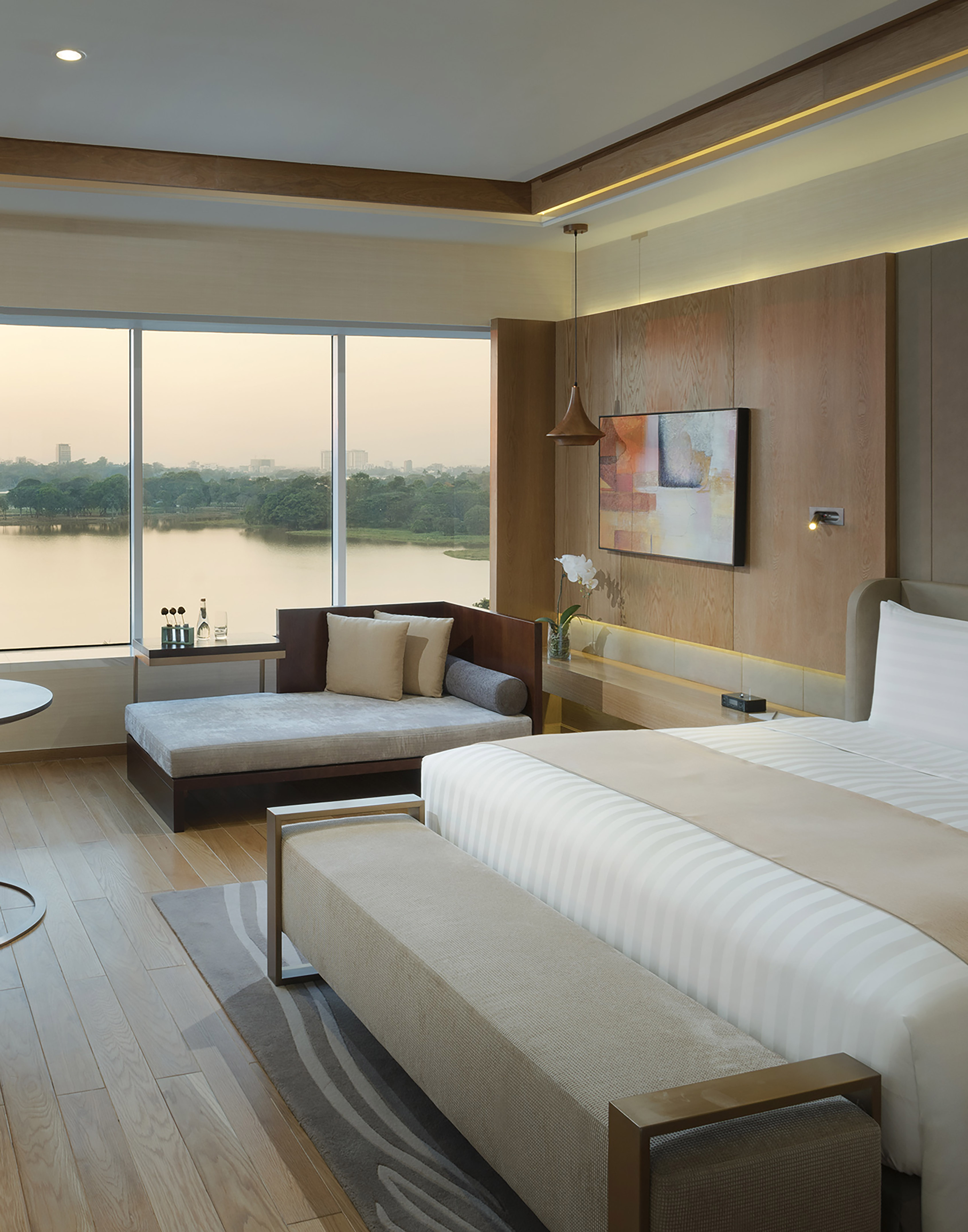 Luxury hotel room with panoramic lake view, comfortable bed, and daybed.