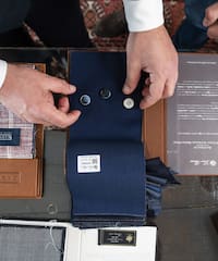 a man's hands holding buttons and a fabric swatch