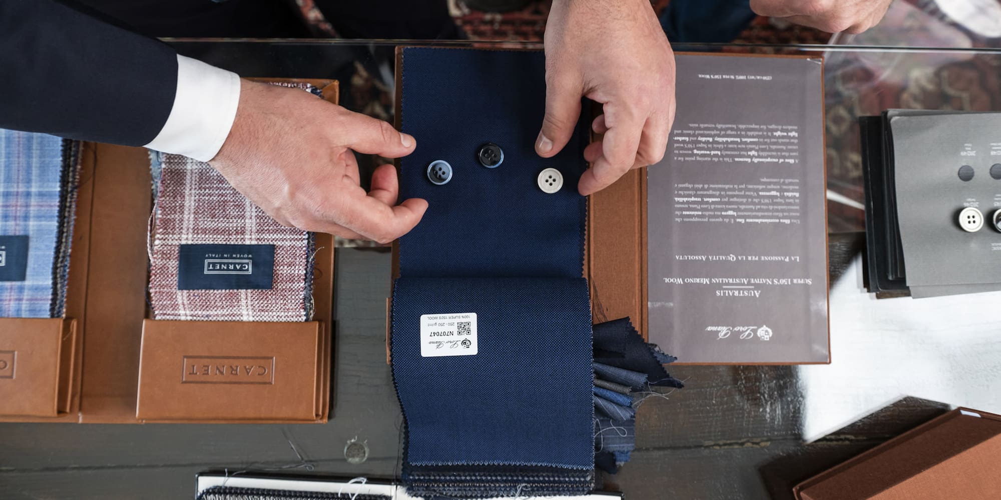 a man's hands holding buttons and a fabric swatch