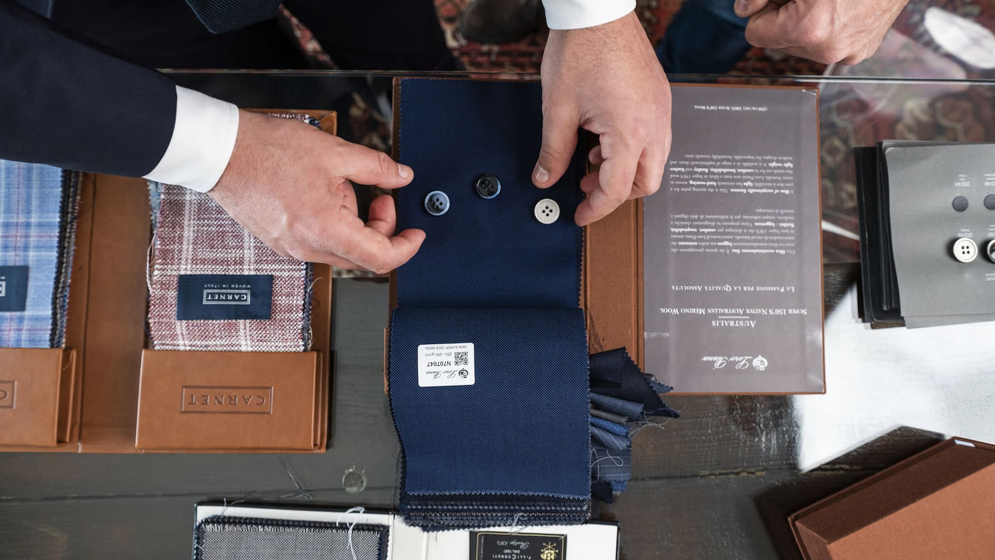 a man's hands holding buttons and a fabric swatch