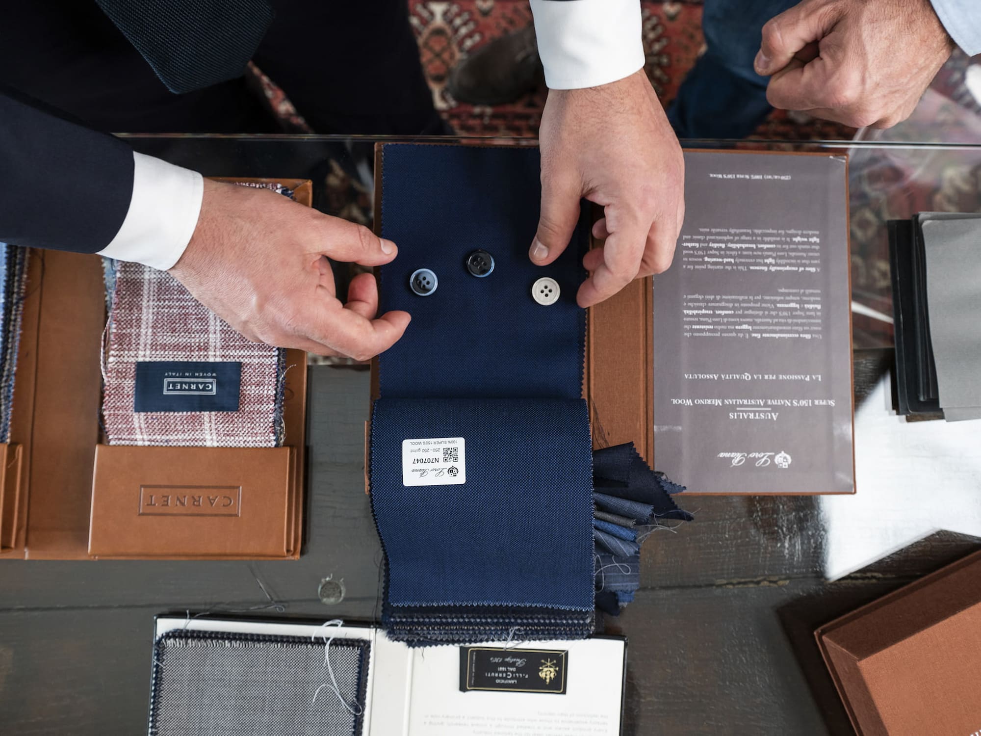 a man's hands holding buttons and a fabric swatch