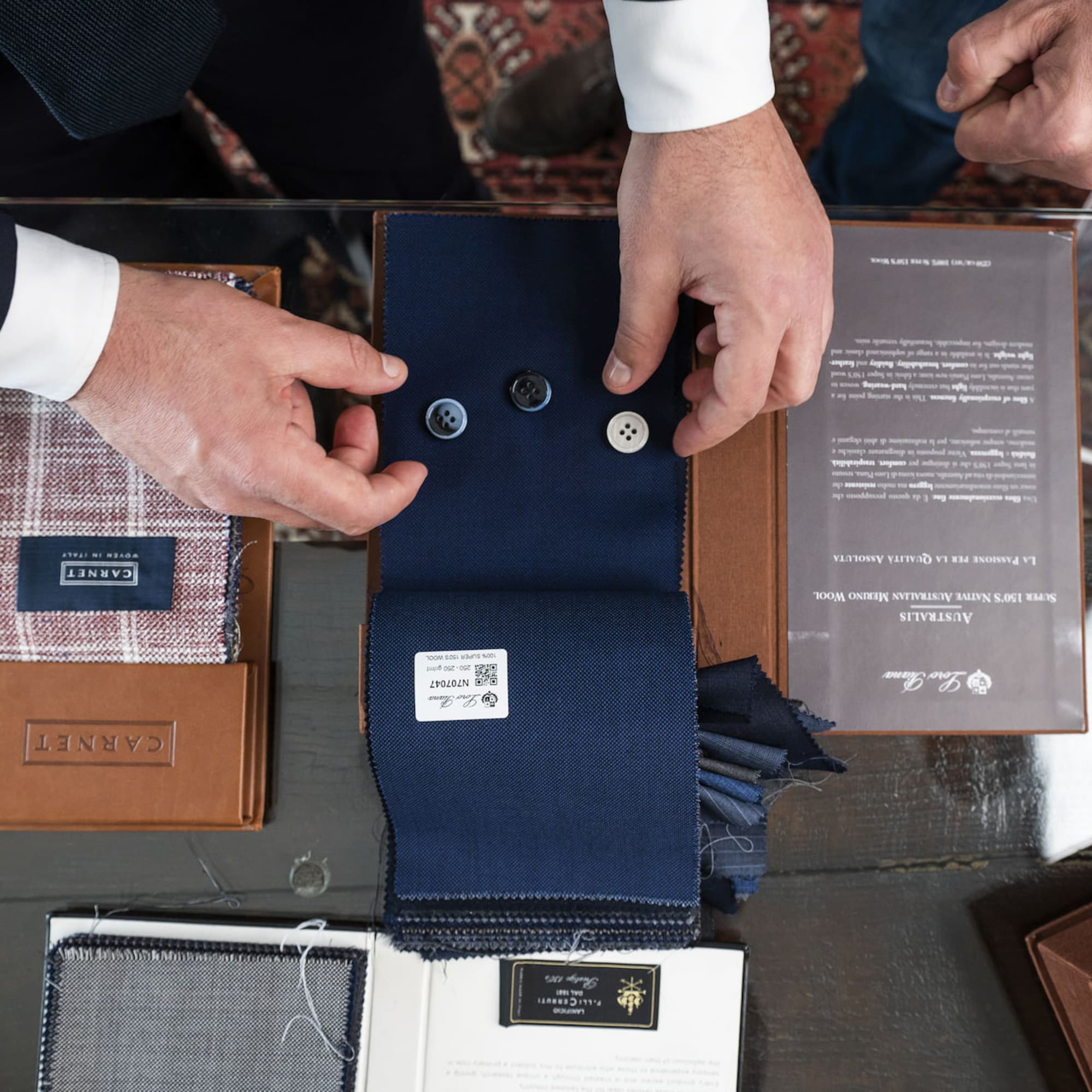 a man's hands holding buttons and a fabric swatch