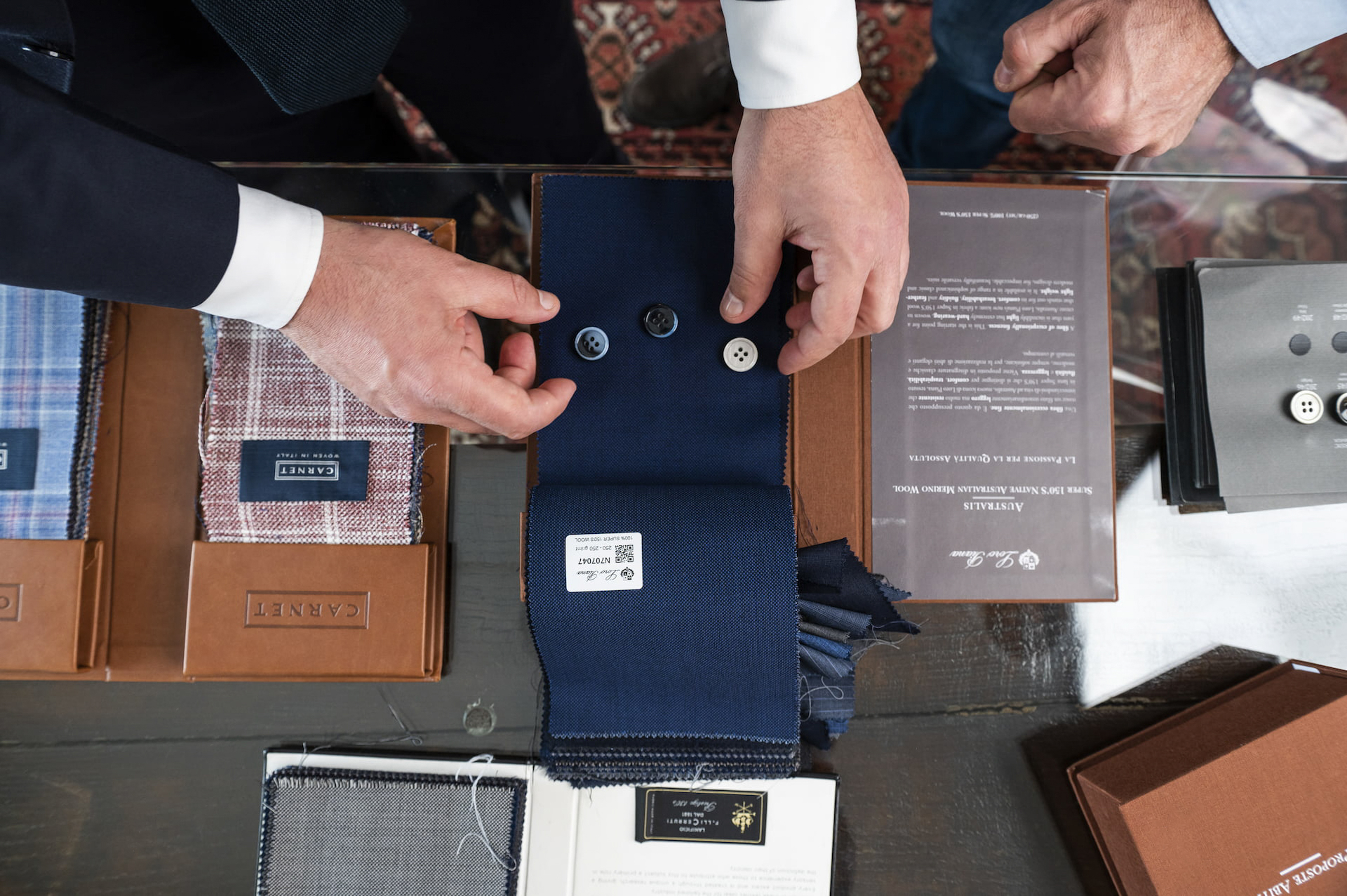 a man's hands holding buttons and a fabric swatch