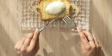 a person eating a piece of bread with butter and a fork